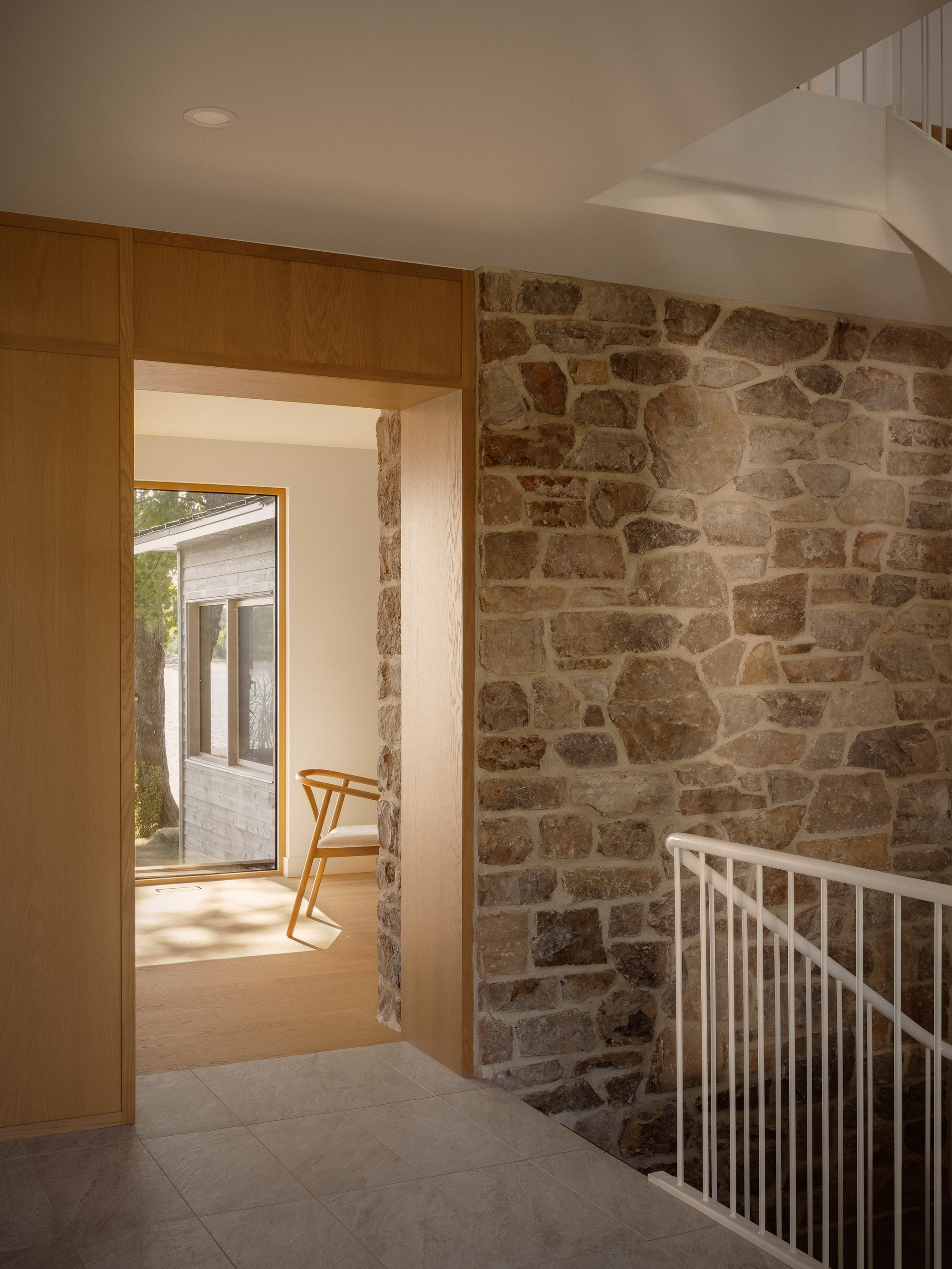 Stairwell landing with exposed stone wall and timber-framed doorway opening to exterior deck beyond