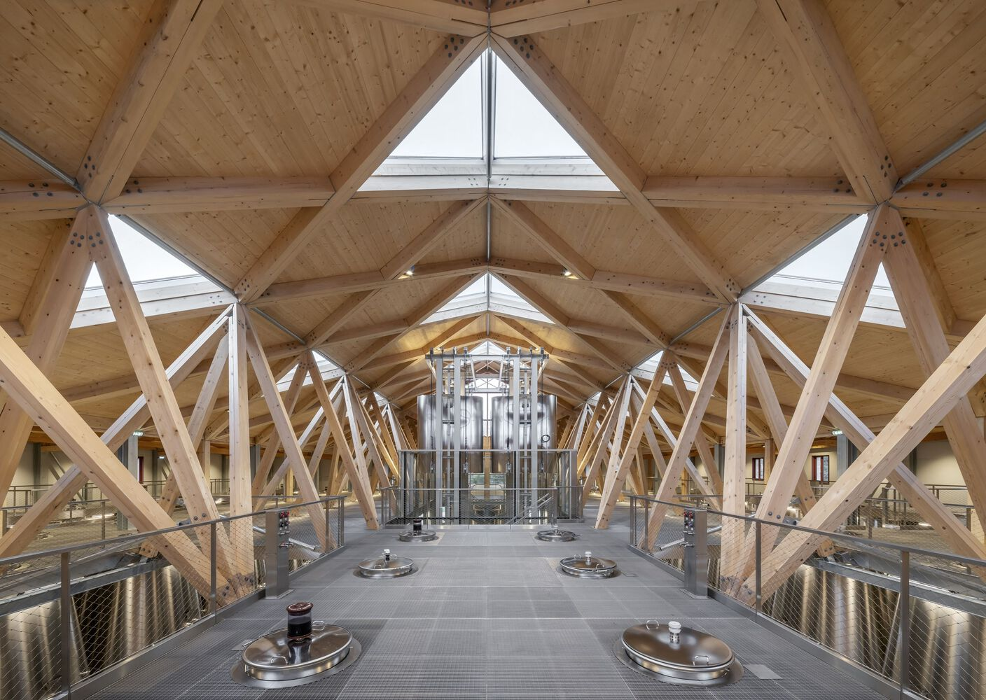View along production hall with triangular skylights in timber truss roof and steel fermentation tanks
