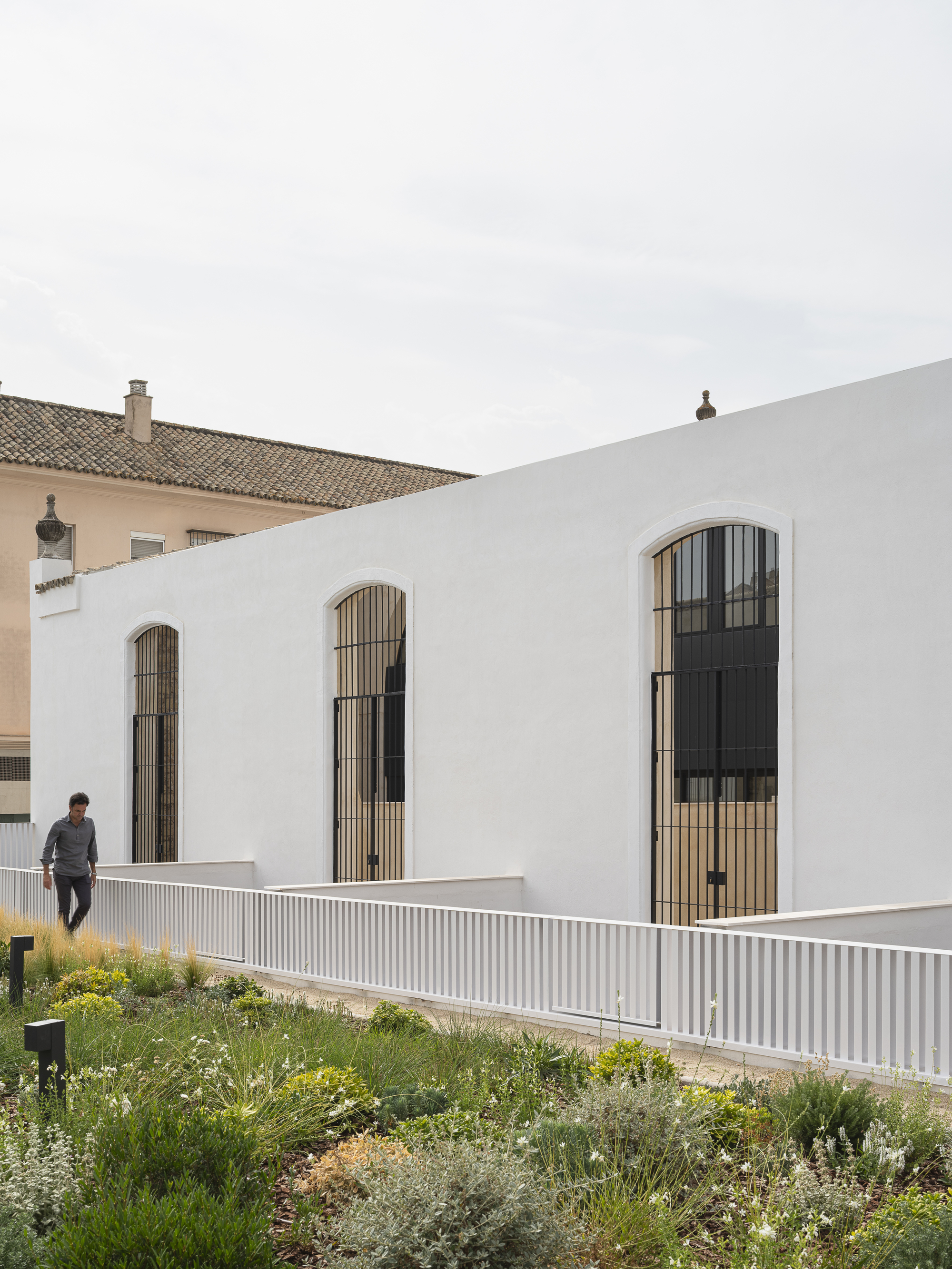 Sequence of arched windows with vertical timber screens along the long facade