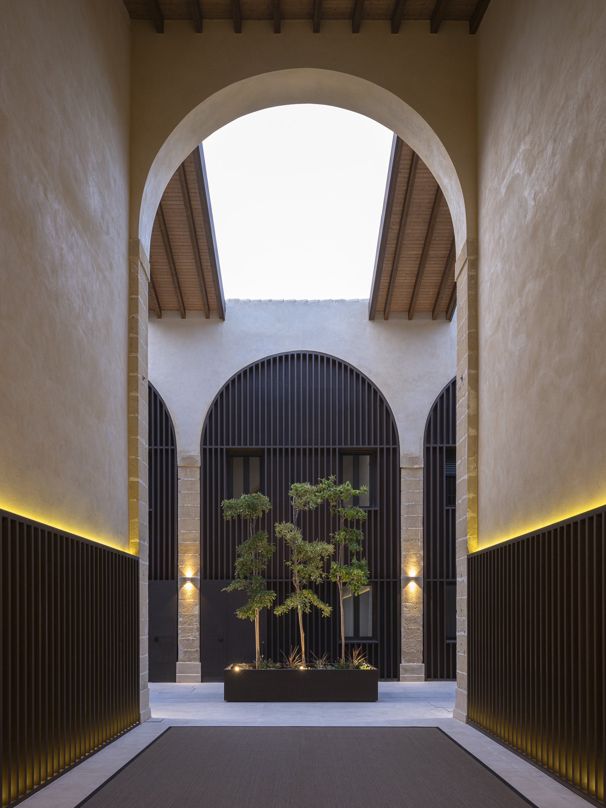 Inner courtyard framed by arches with a planted feature beyond timber screens