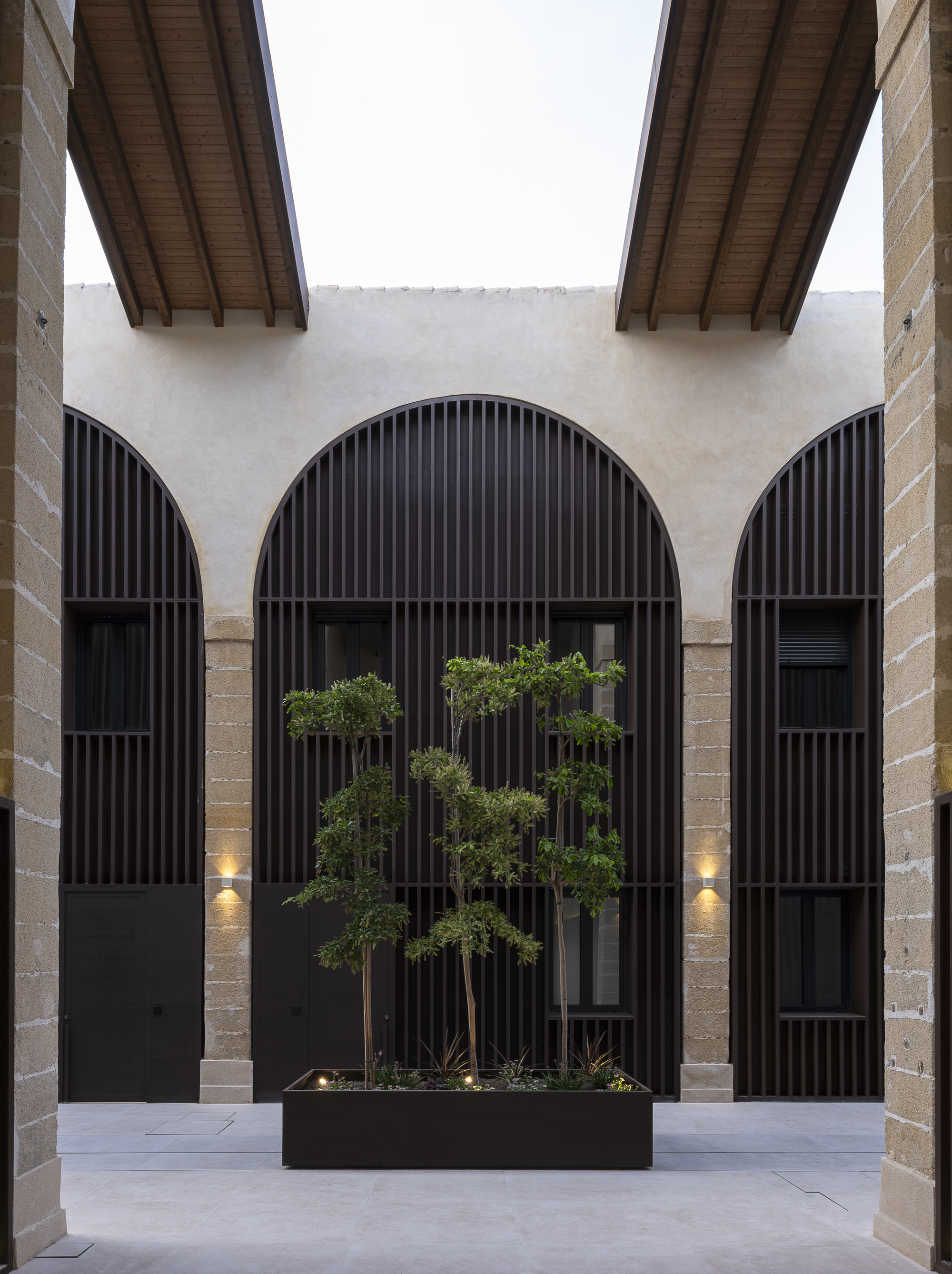 Internal courtyard with arched openings and dark vertical timber screens