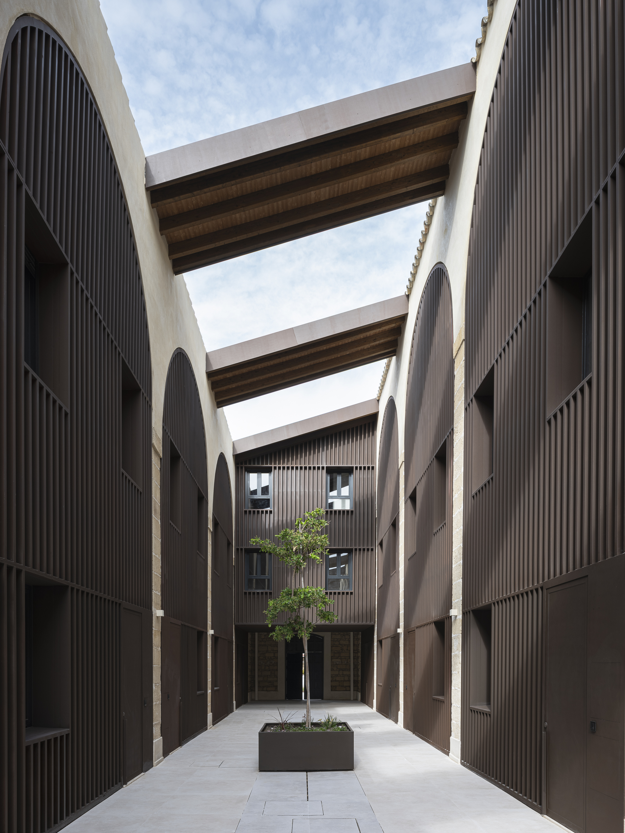 Long courtyard between residential blocks with cross beams and a tree