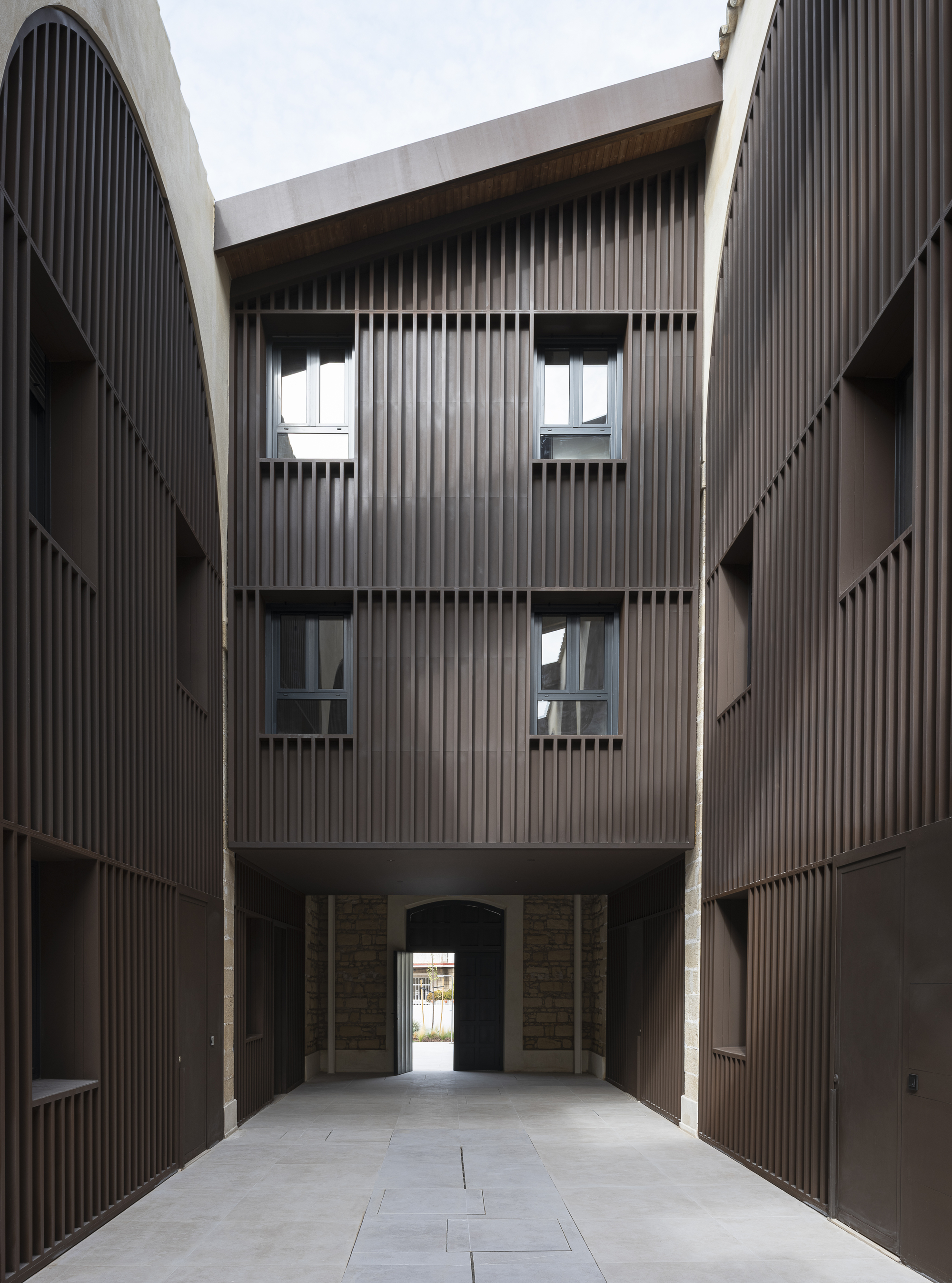 Internal alley culminating in a tall residential facade above a passage