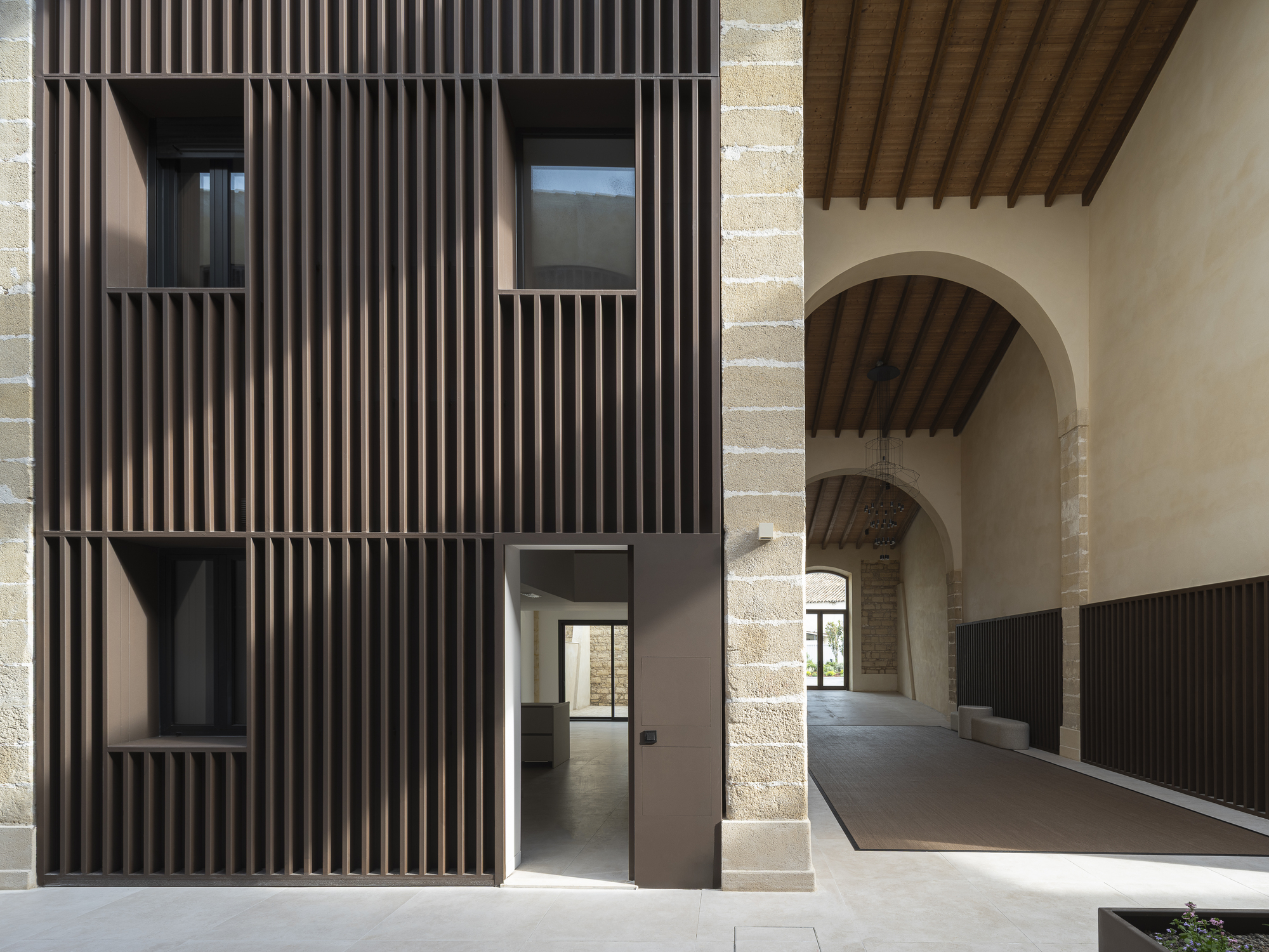 Doorway through a slatted facade adjacent to a vaulted timber ceiling