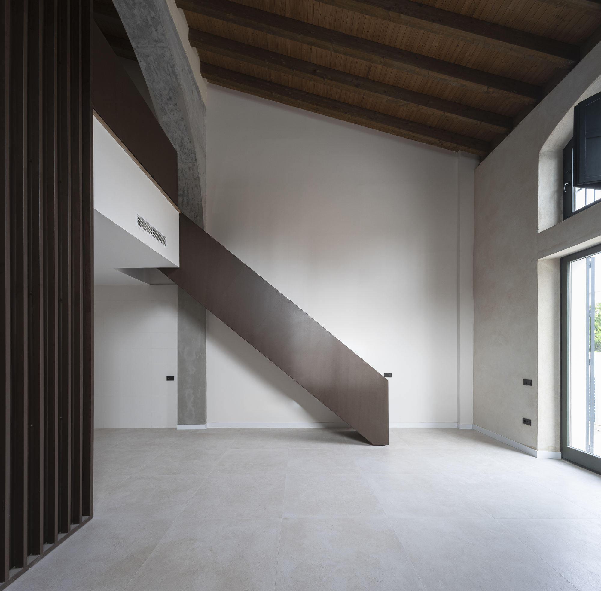 Double-height interior with original timber roof and a steel stair