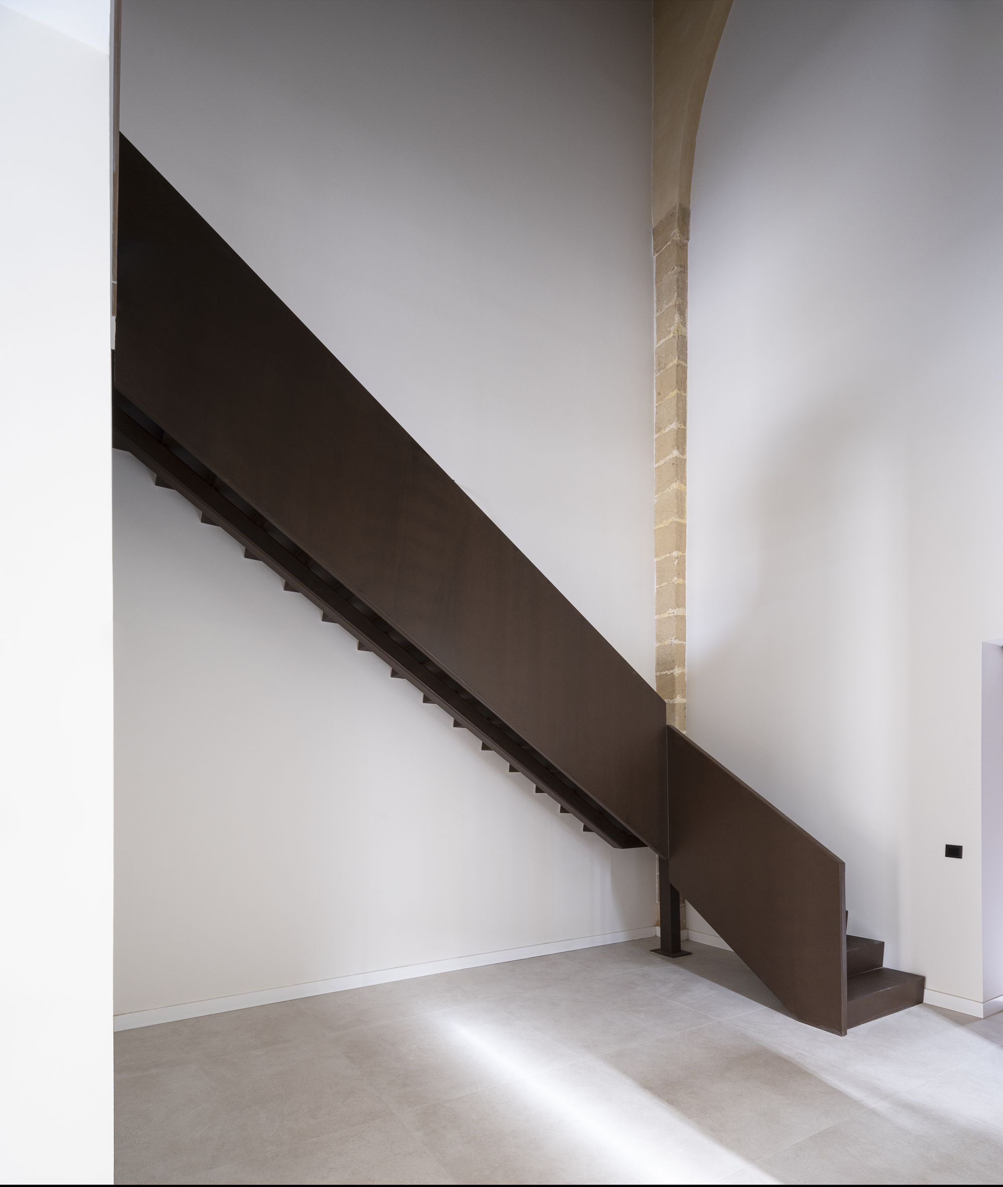 Steel stair against an exposed sandstone column inside a unit