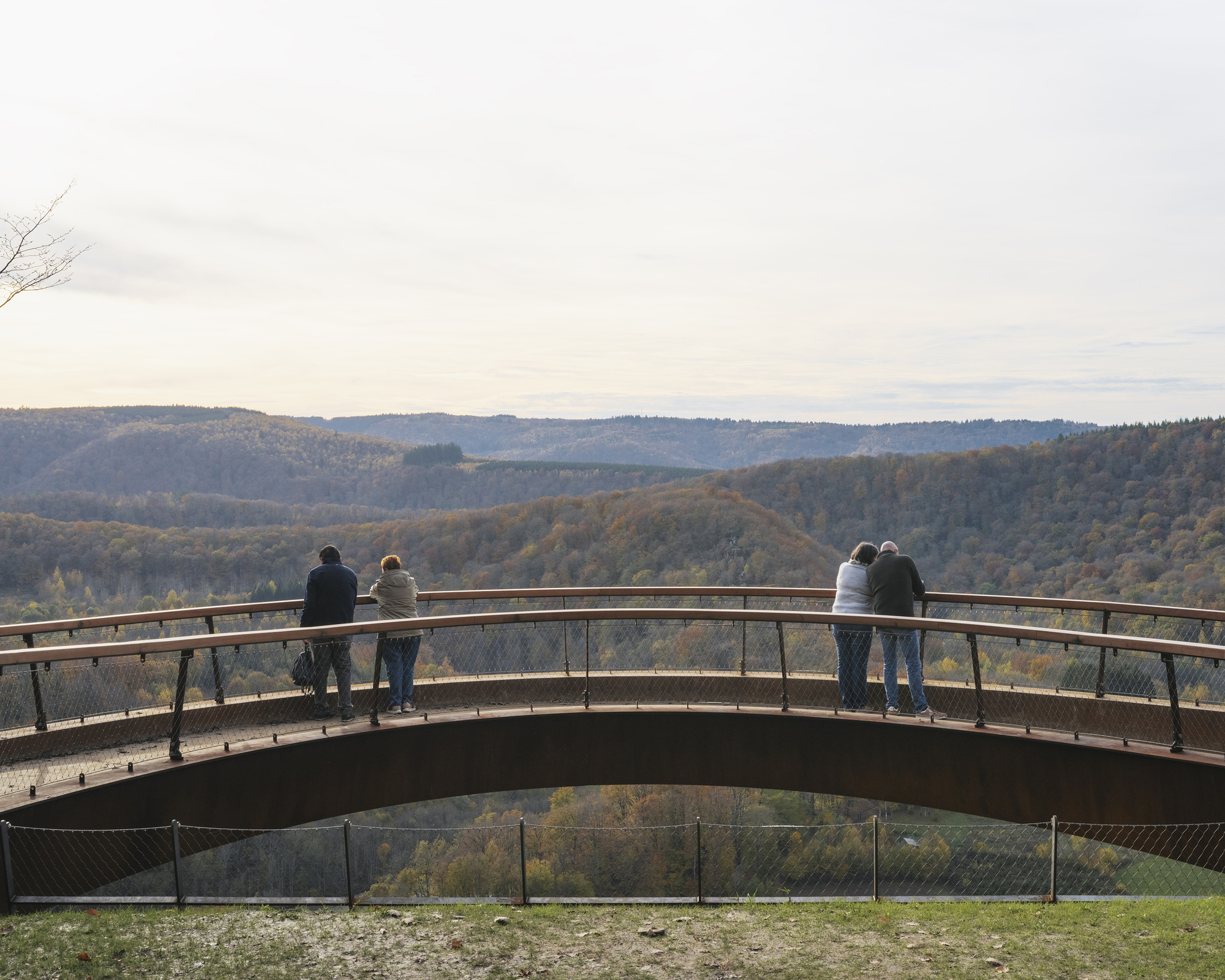 Couples leaning over the railing of the curving walkway at sunset
