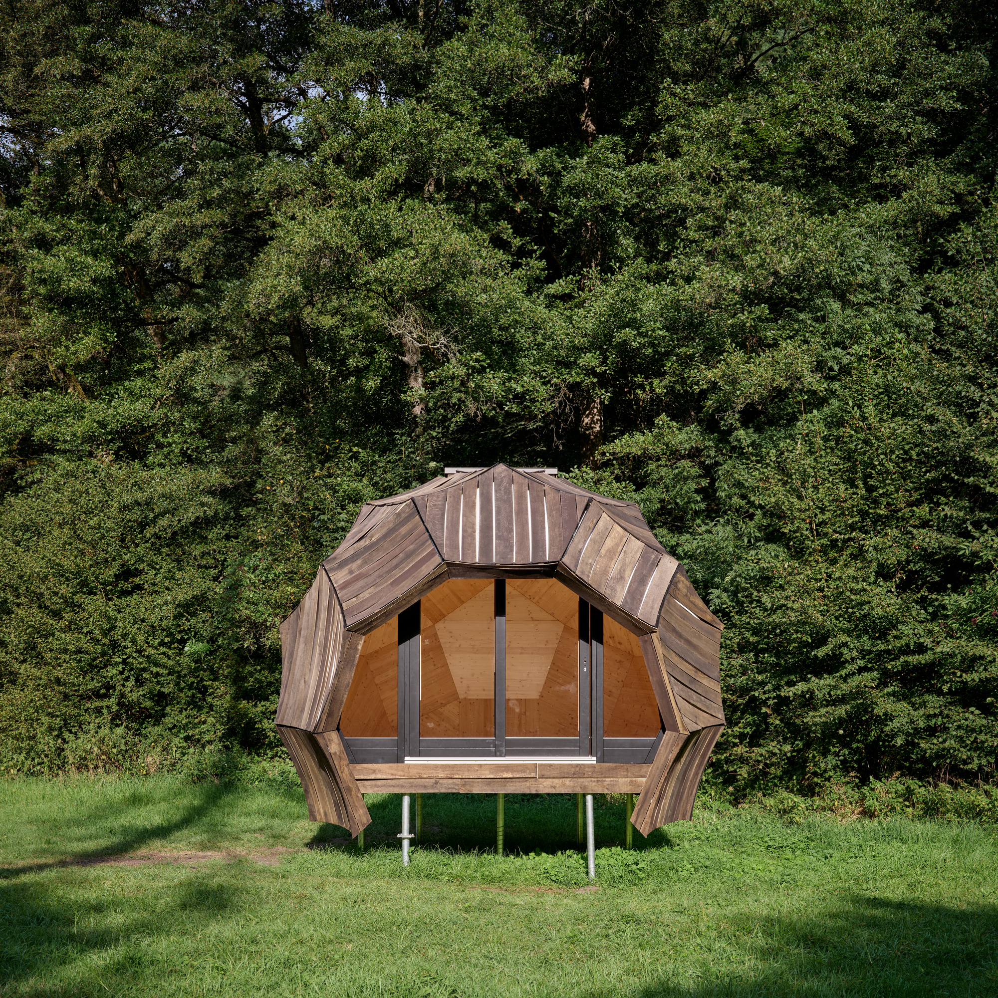 Front elevation of the faceted timber pavilion showing plywood door panels and metal standing seam roof