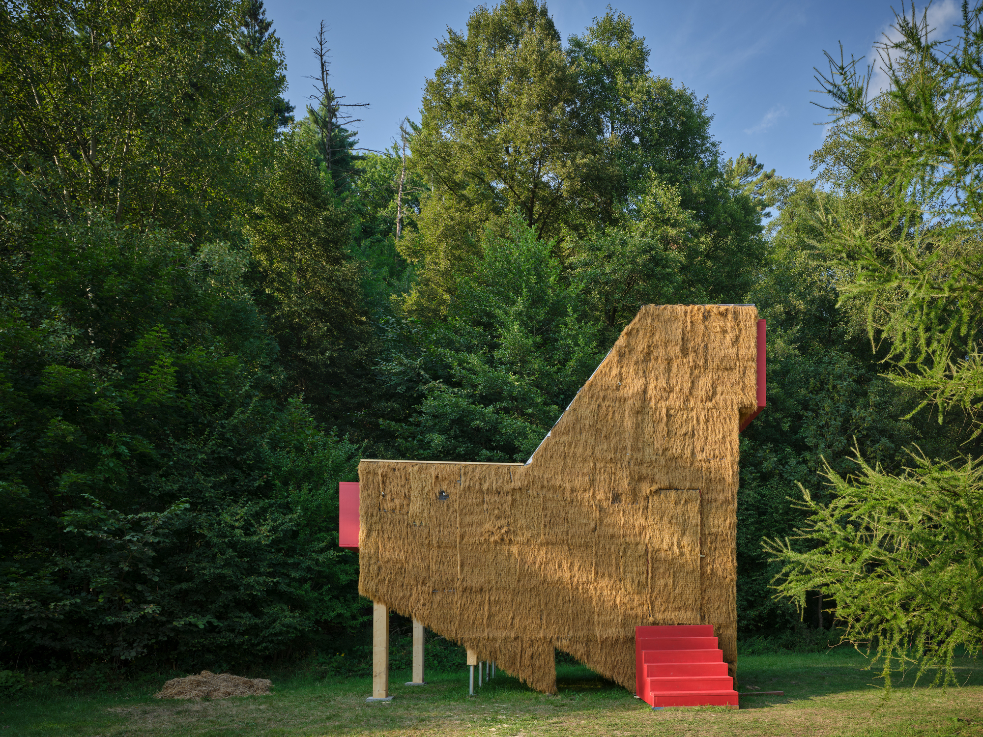 Profile view of the elevated straw bale structure showing angular roofline and red access stair