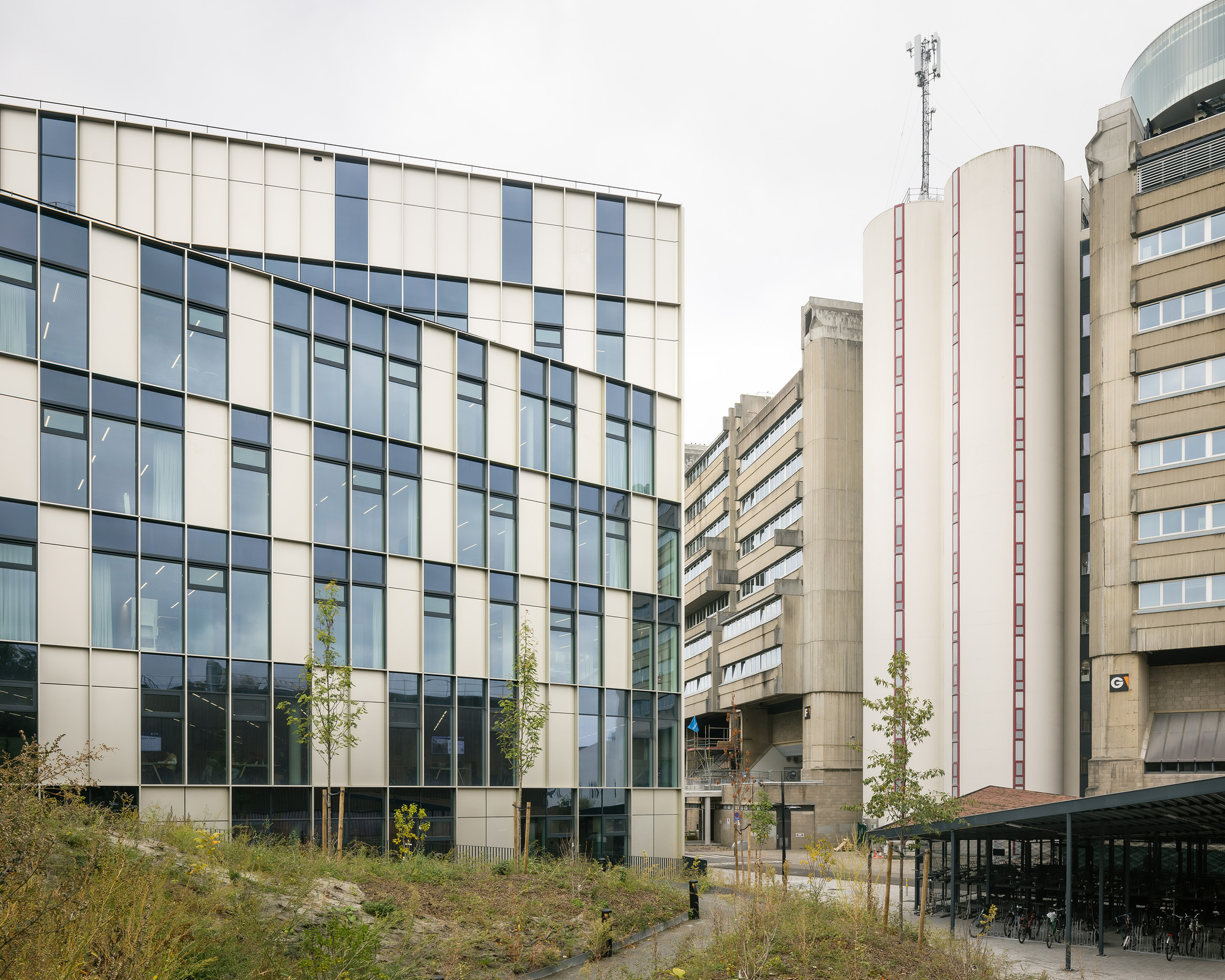 The building set against the existing brutalist campus towers