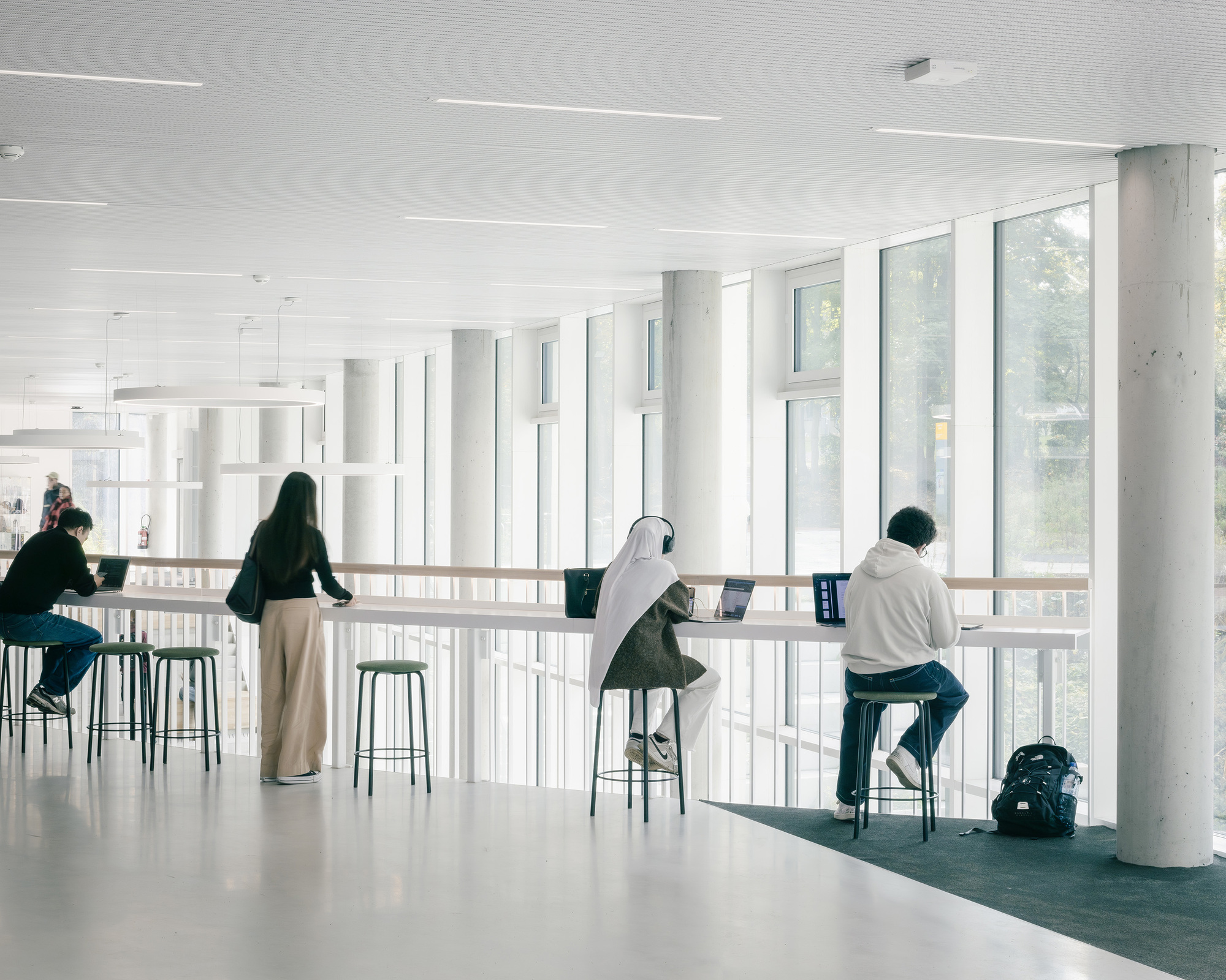 Upper-level study counter with bar stools along a fully glazed wall