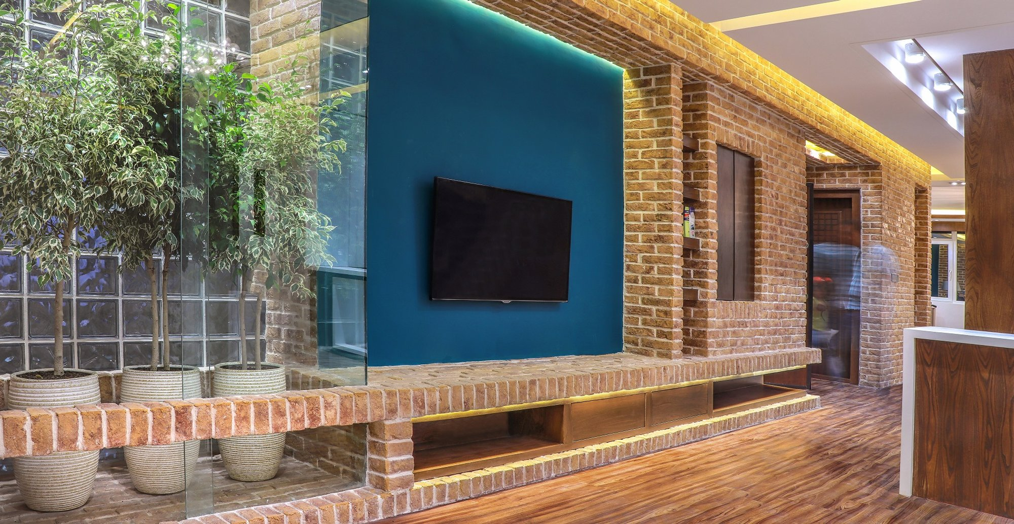 Integrated greenery and glass soften the brick interior, enhancing light and spatial depth.