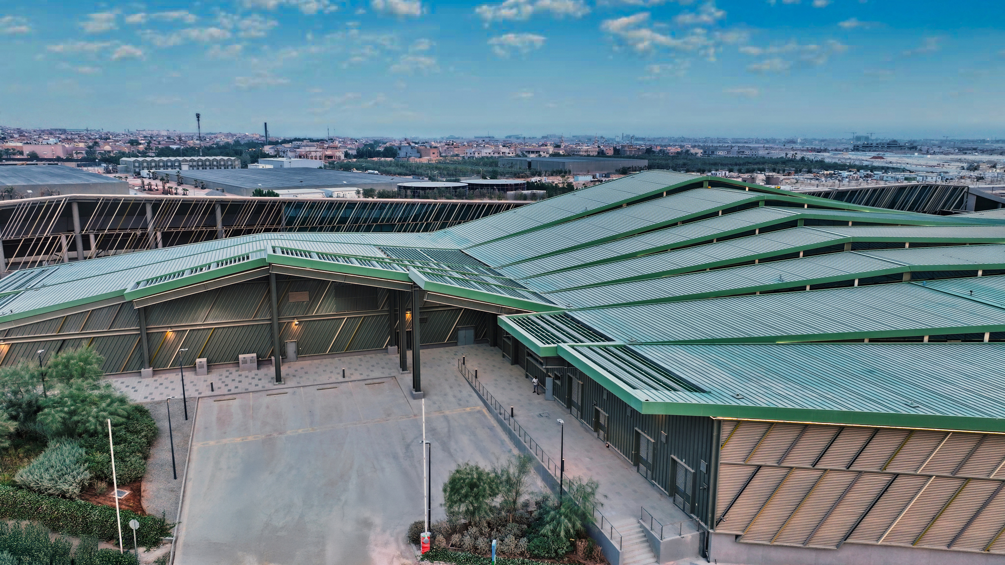 Aerial view of the undulating green metal roofs with integrated solar panels under a blue sky