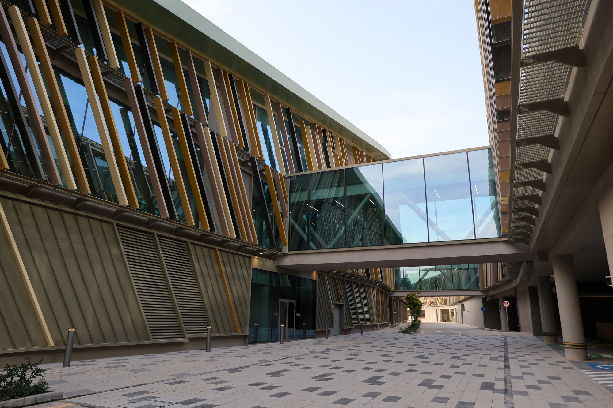 Interior courtyard with angled timber louvers and a glazed bridge connecting two volumes