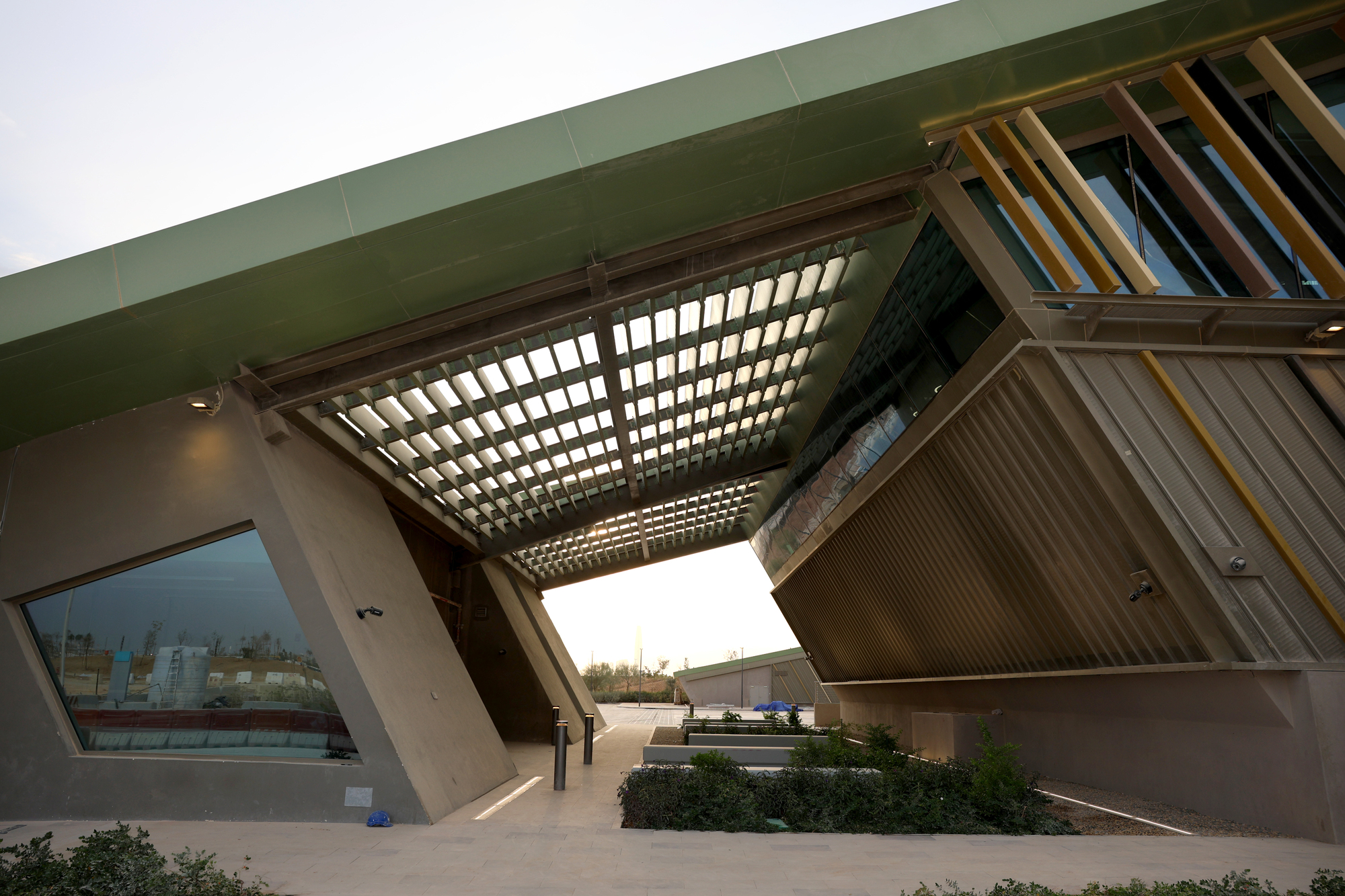 Upward view of the timber brise-soleil canopy framing the angled facade above