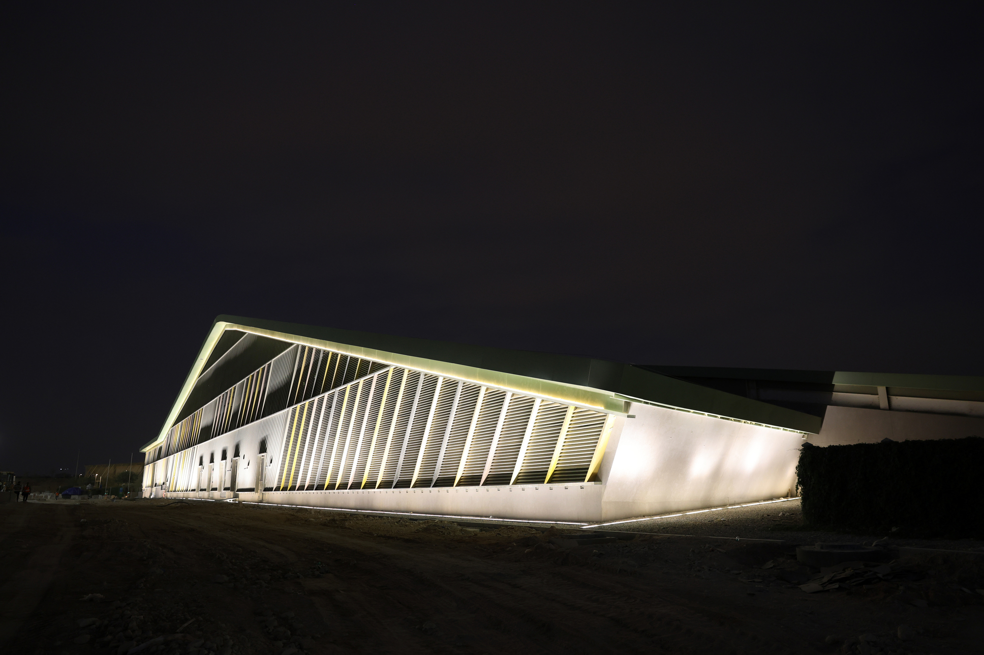 Corner view of the angular volume with vertical white fins and uplighting at night