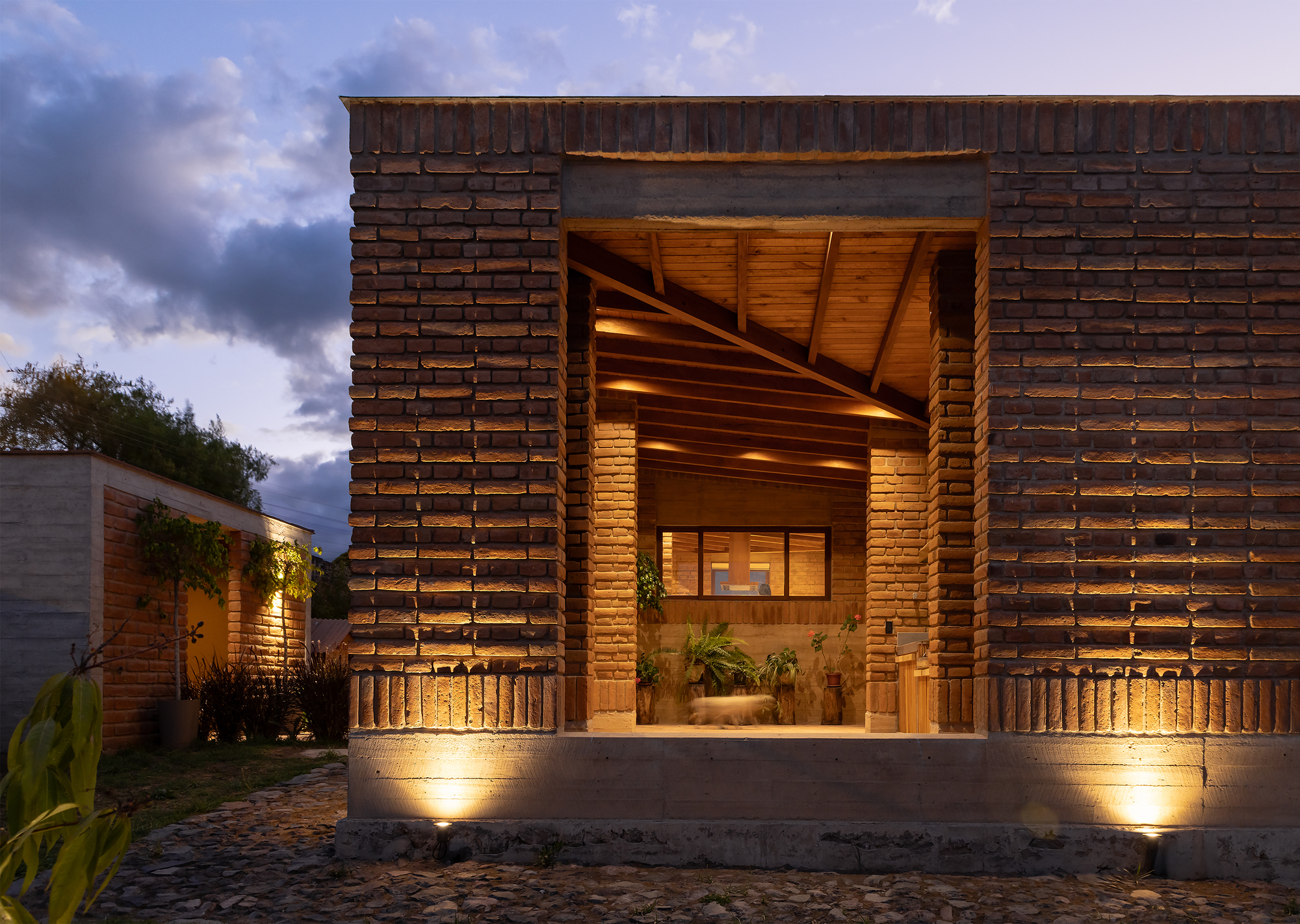 Front facade with stacked brick screen walls and recessed timber entry at dusk