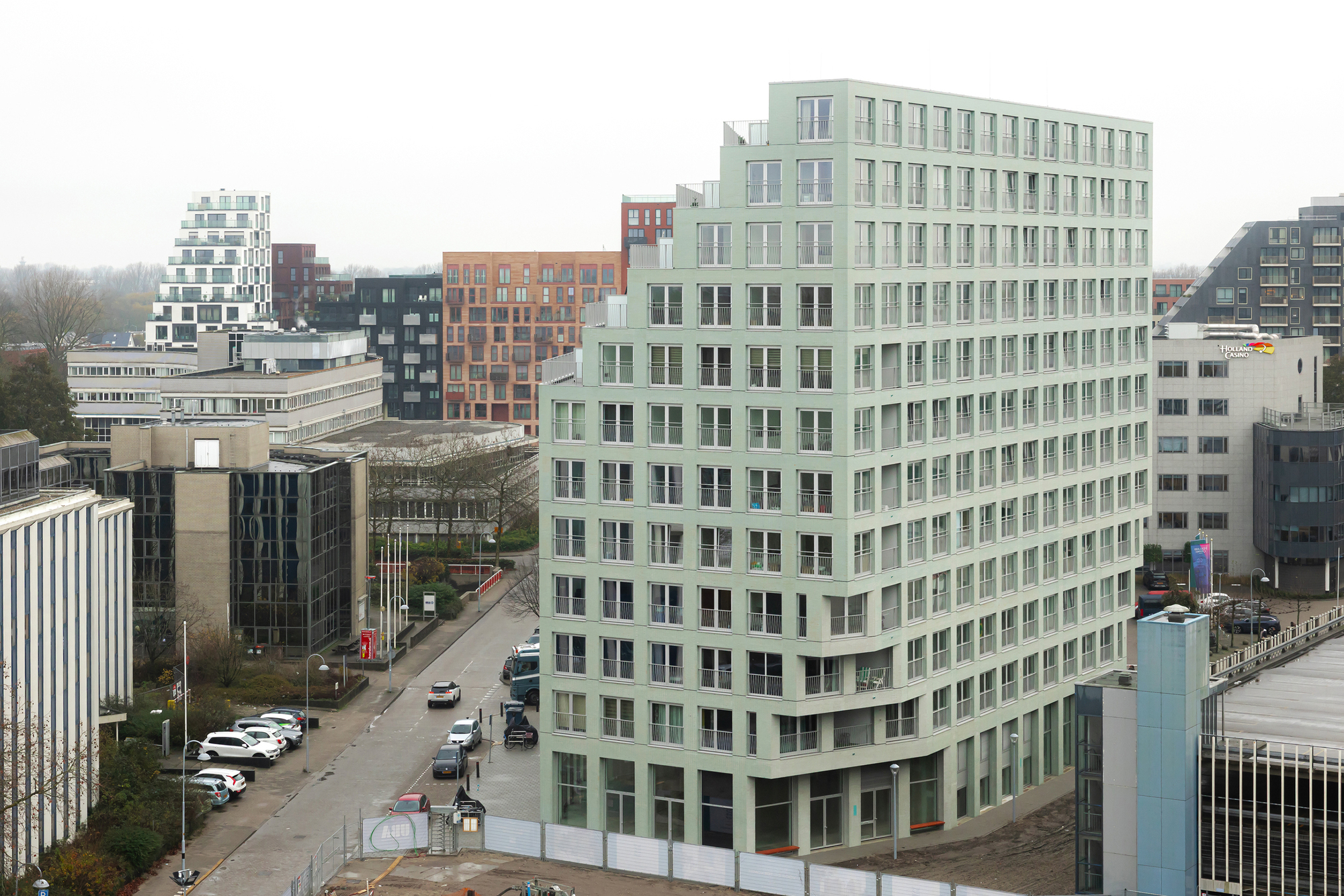 Elevated view of the pale green facade with regular window grid overlooking surrounding urban blocks