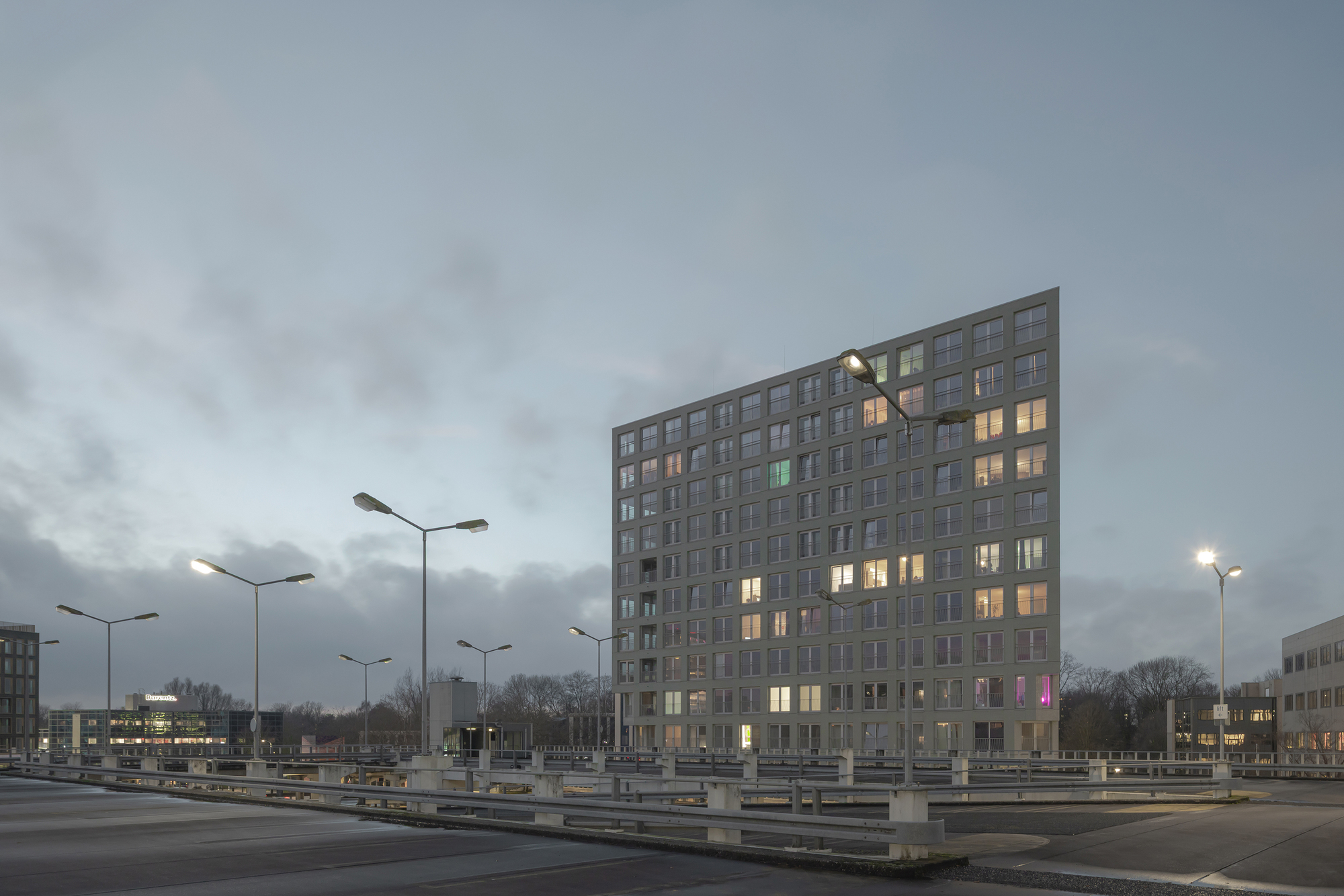 Tower viewed from the highway median at dusk with illuminated windows and streetlights