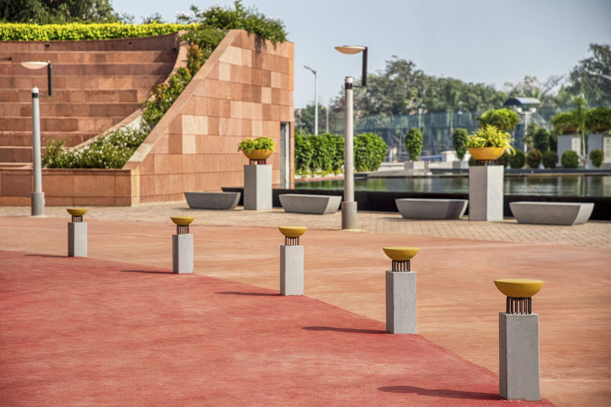 Outdoor terrace with stepped sandstone seating and short concrete bollards topped with golden discs