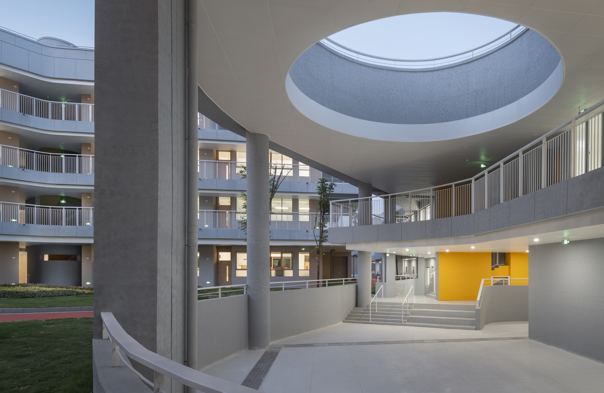 Interior atrium with circular skylight above concrete columns and tiered balconies overlooking a central courtyard