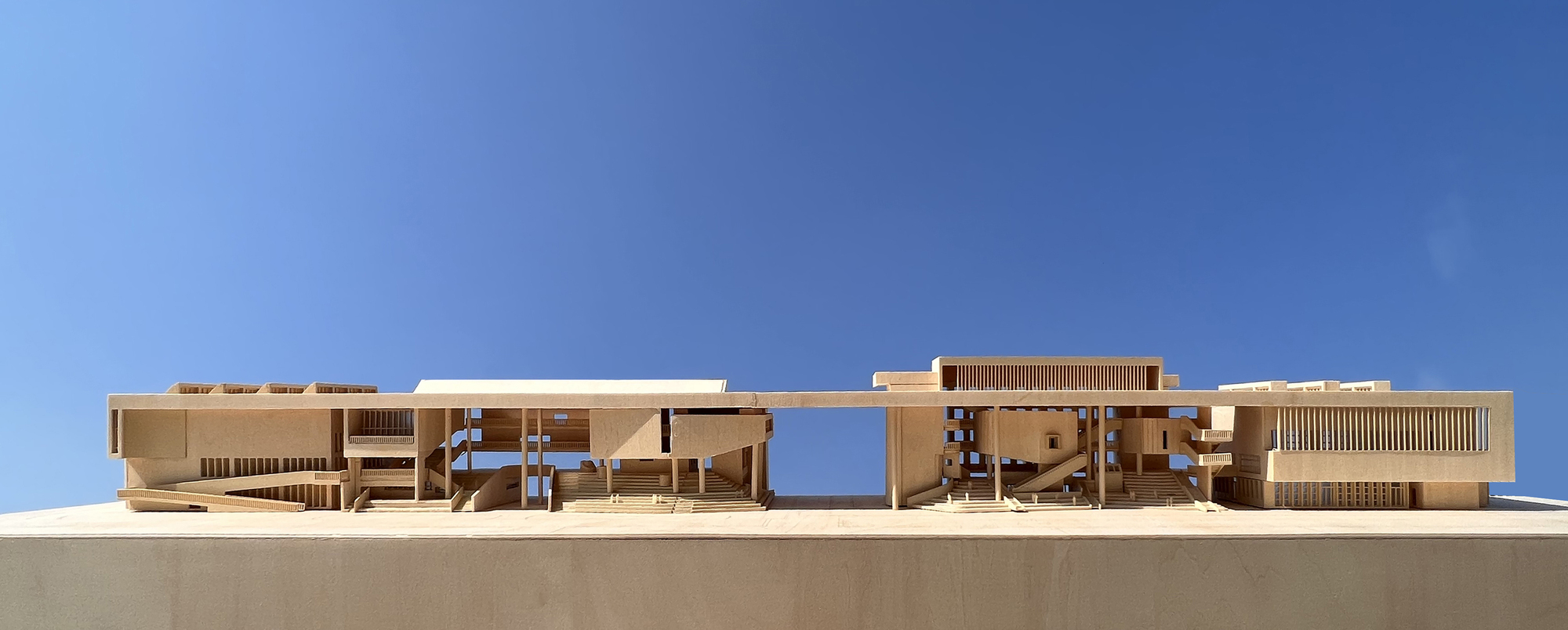 Section model showing layered horizontal volumes with timber screens and central courtyards cutting through the mass