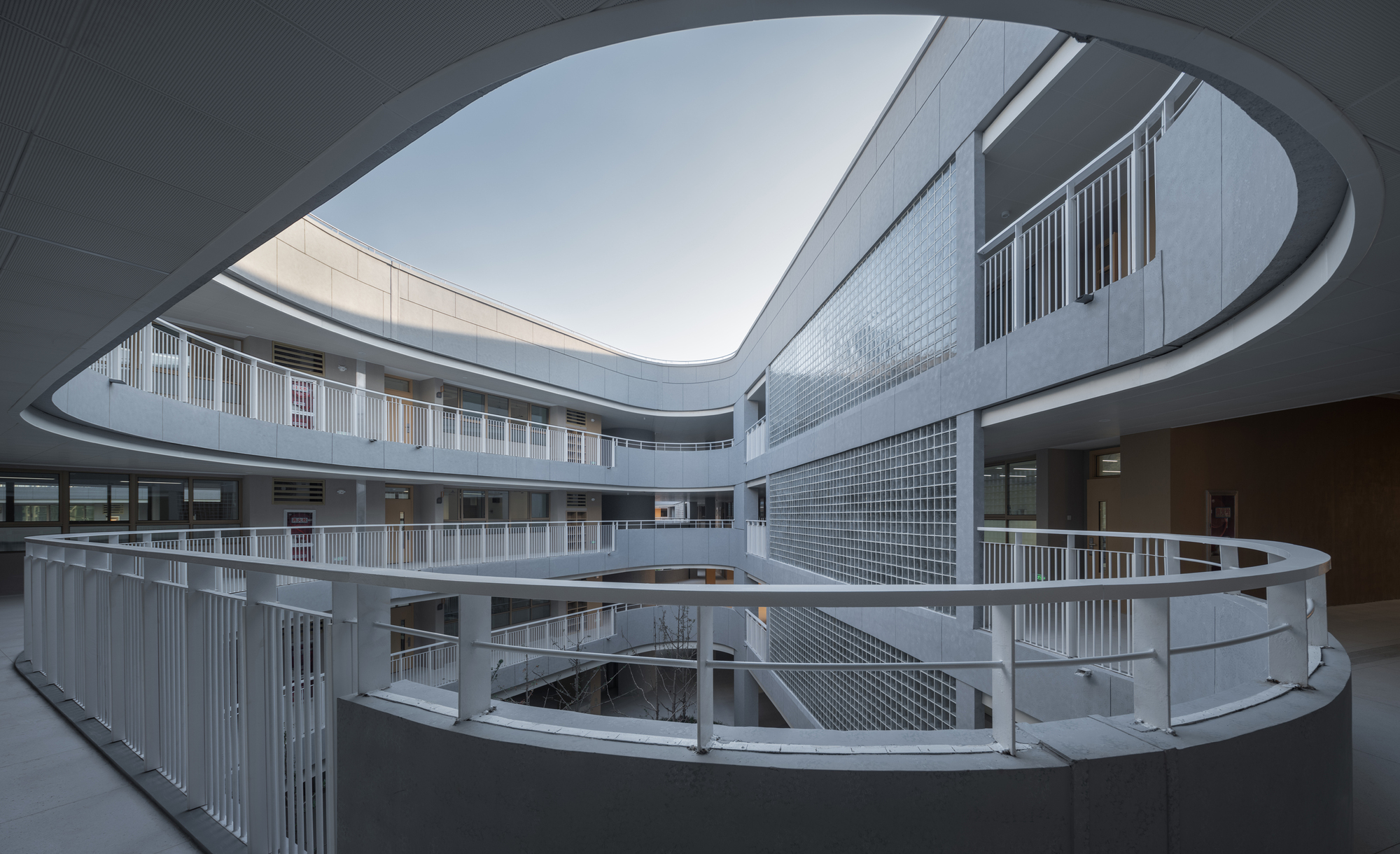 Curved white railings wrapping around a multilevel oval courtyard beneath an open sky