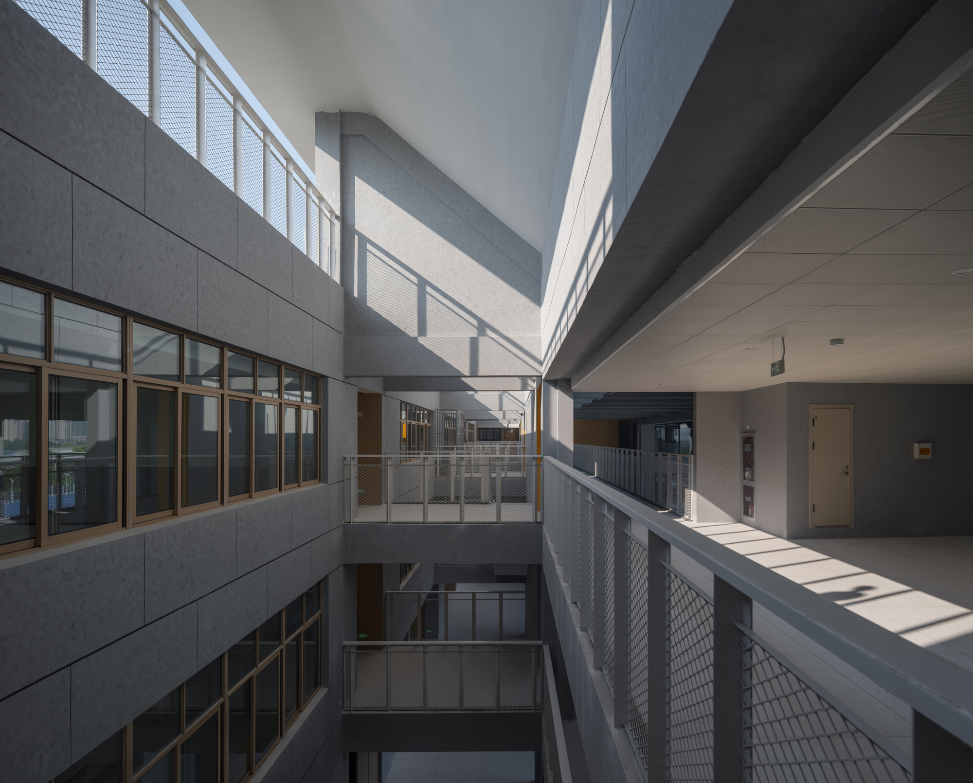 Multilevel courtyard with metal mesh railings and morning sunlight casting sharp shadows