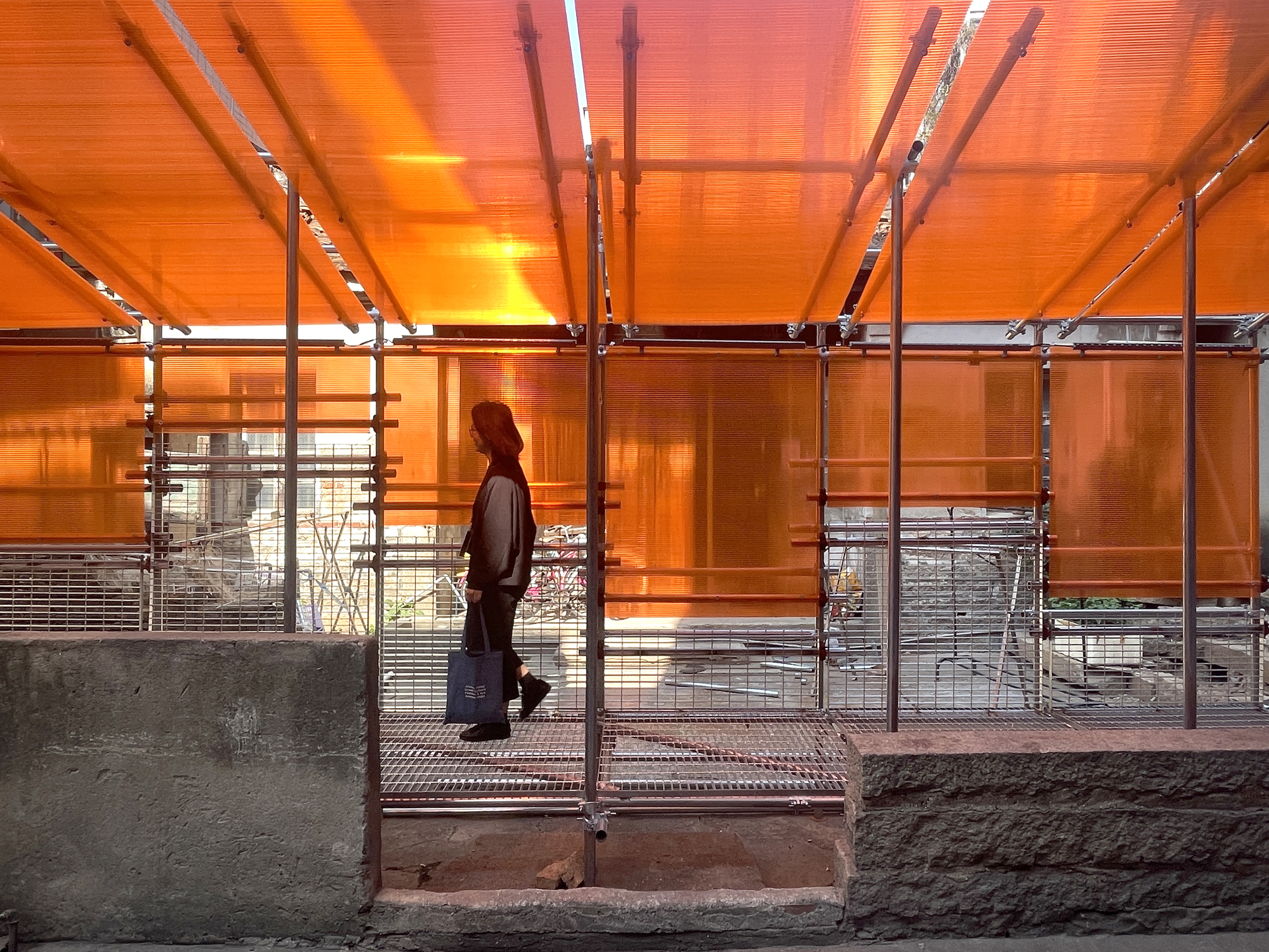 Interior view beneath the illuminated orange canopy with a silhouetted figure standing at the threshold