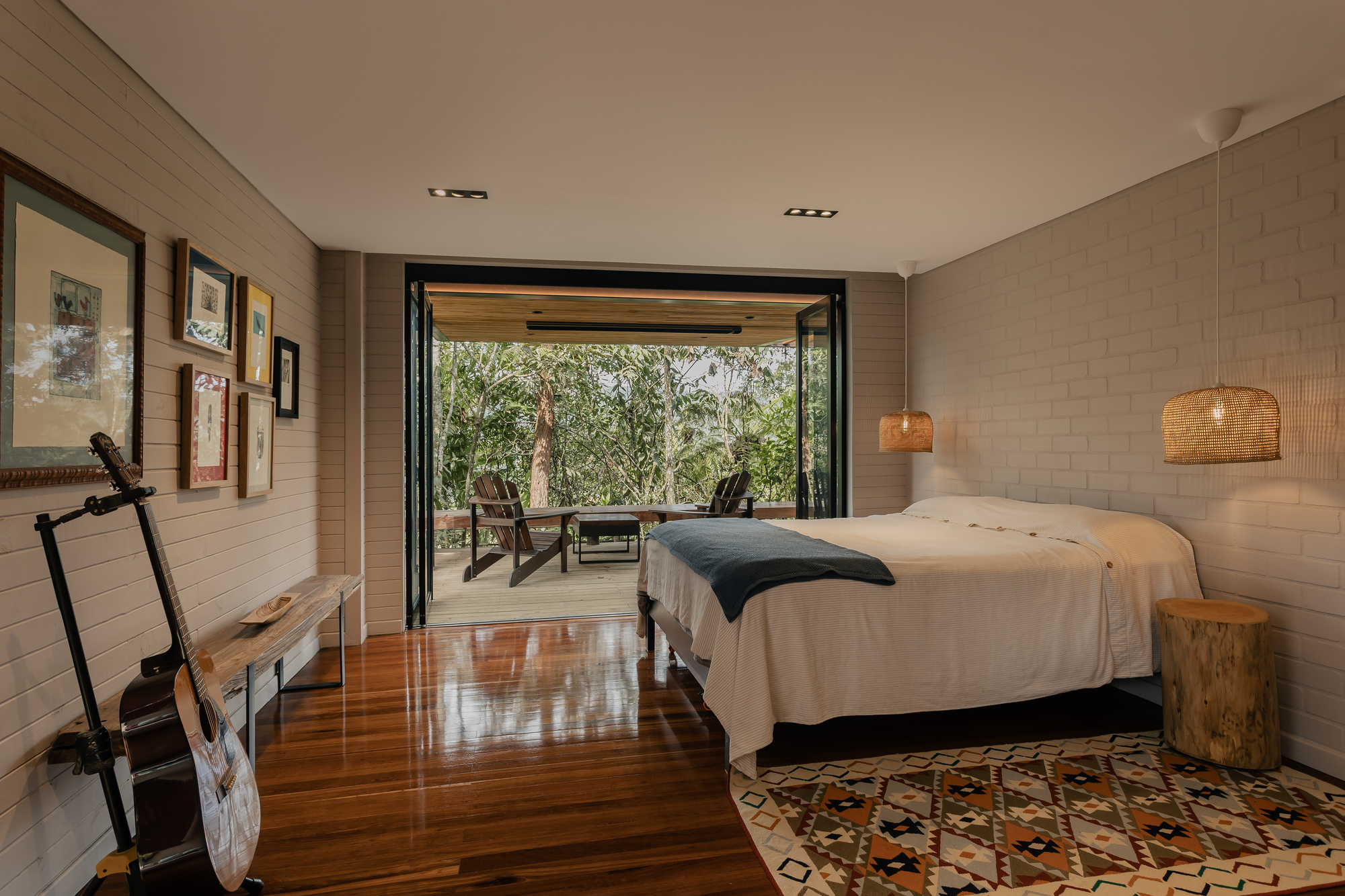 Bedroom with folding glass doors opening to a covered terrace among the trees