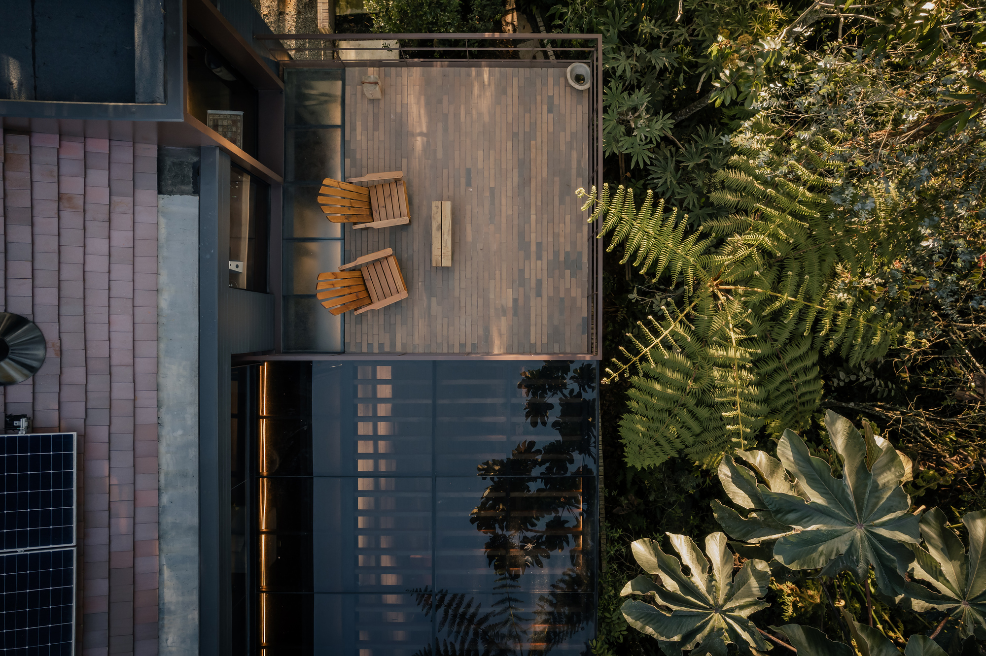 Aerial view of timber deck terrace with two folding chairs beside ferns and tropical foliage
