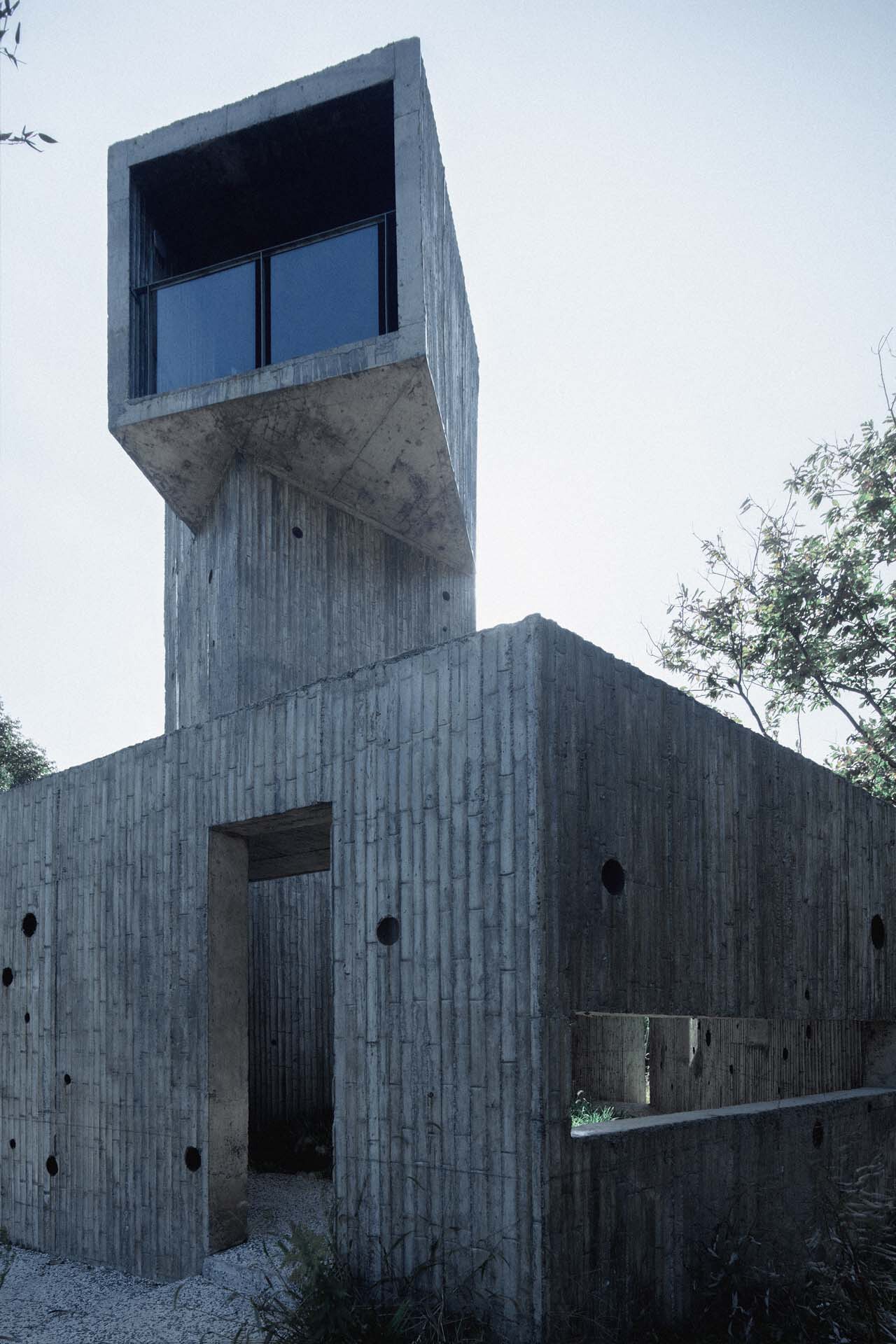 Close view of the cantilevered observation room atop the board-formed concrete tower at dusk