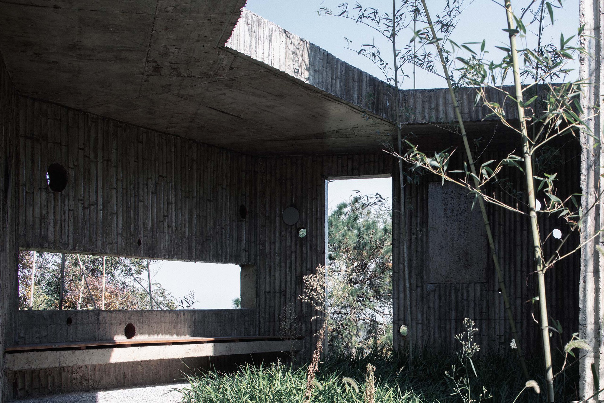 Covered terrace with ribbed concrete ceiling and horizontal window framing the hillside beyond