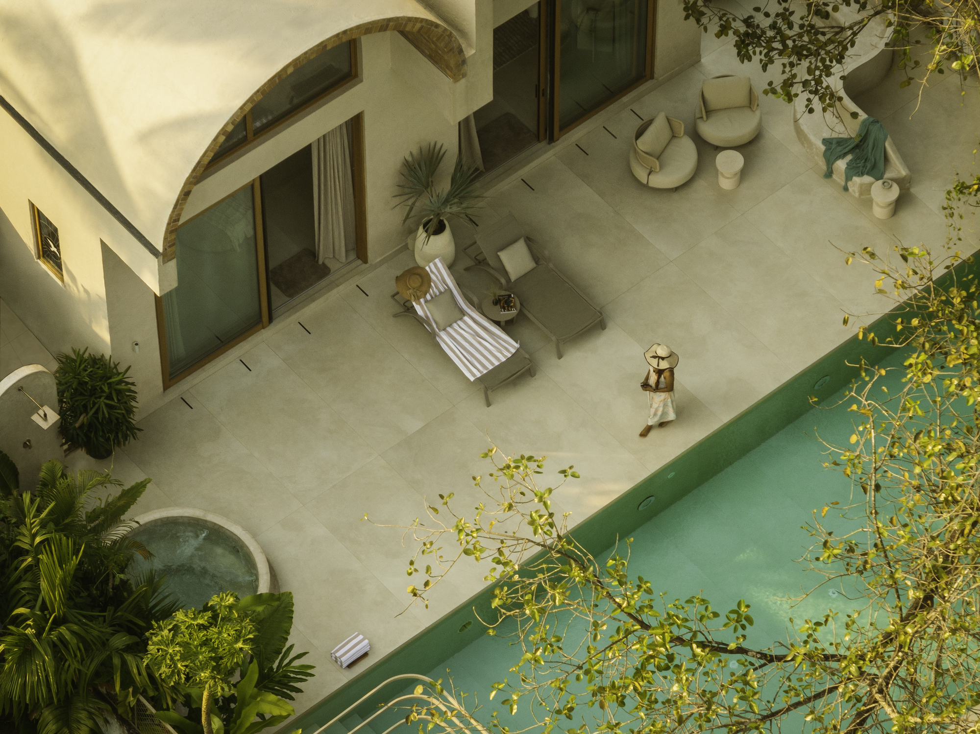 Overhead view of the courtyard terrace with person walking beside the pool at golden hour