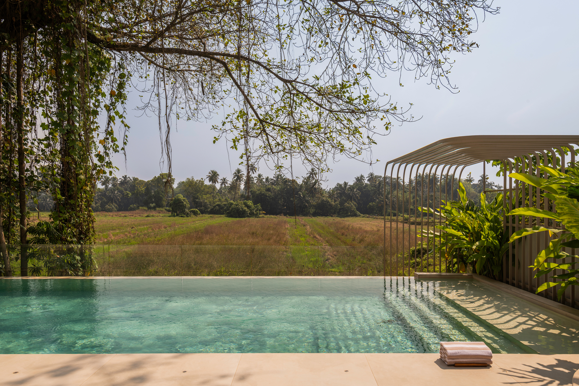 Pool deck with curved metal screen structure framing views of the agricultural landscape beyond