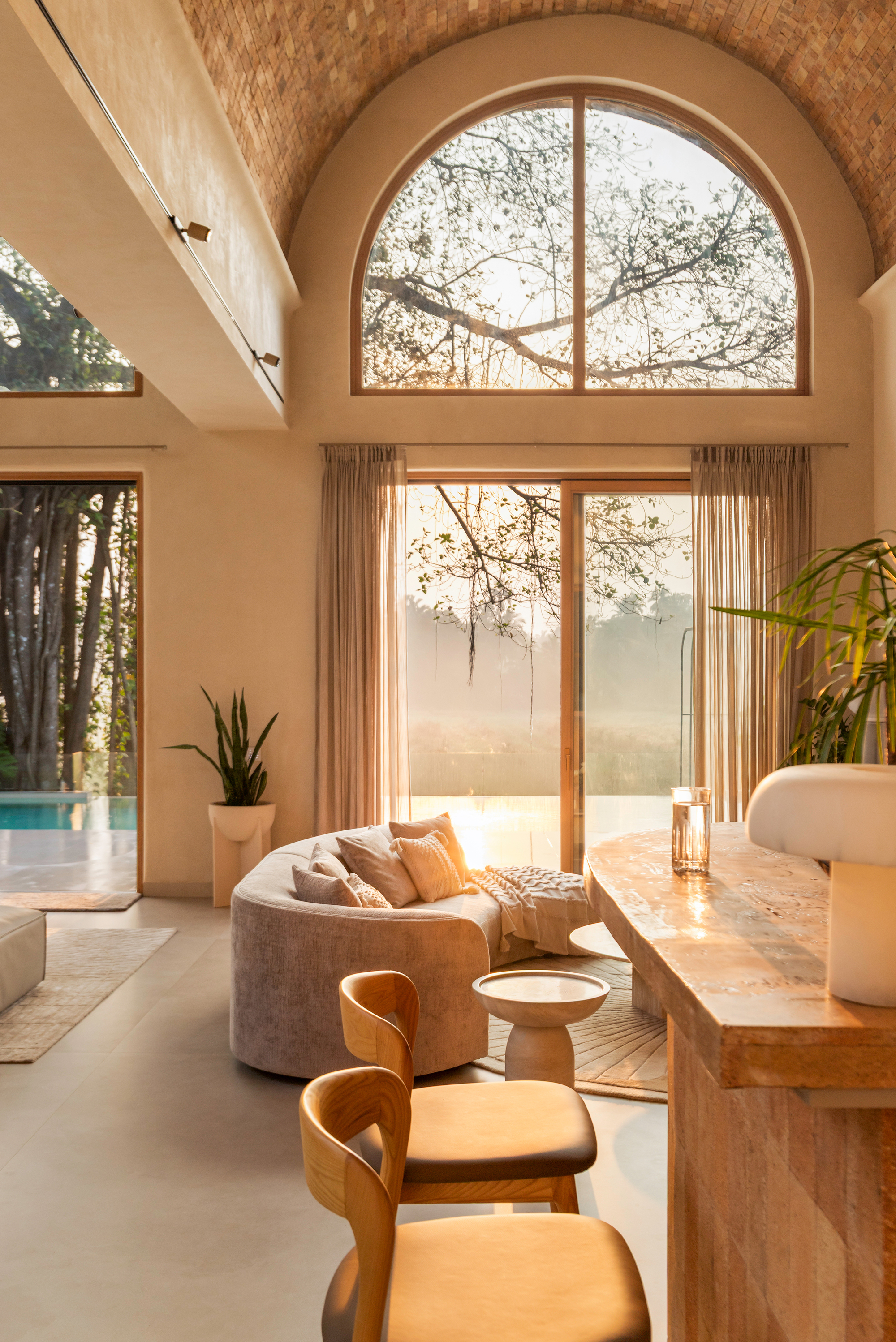 Living area with vaulted brick ceiling and arched glass doors opening to pool terrace