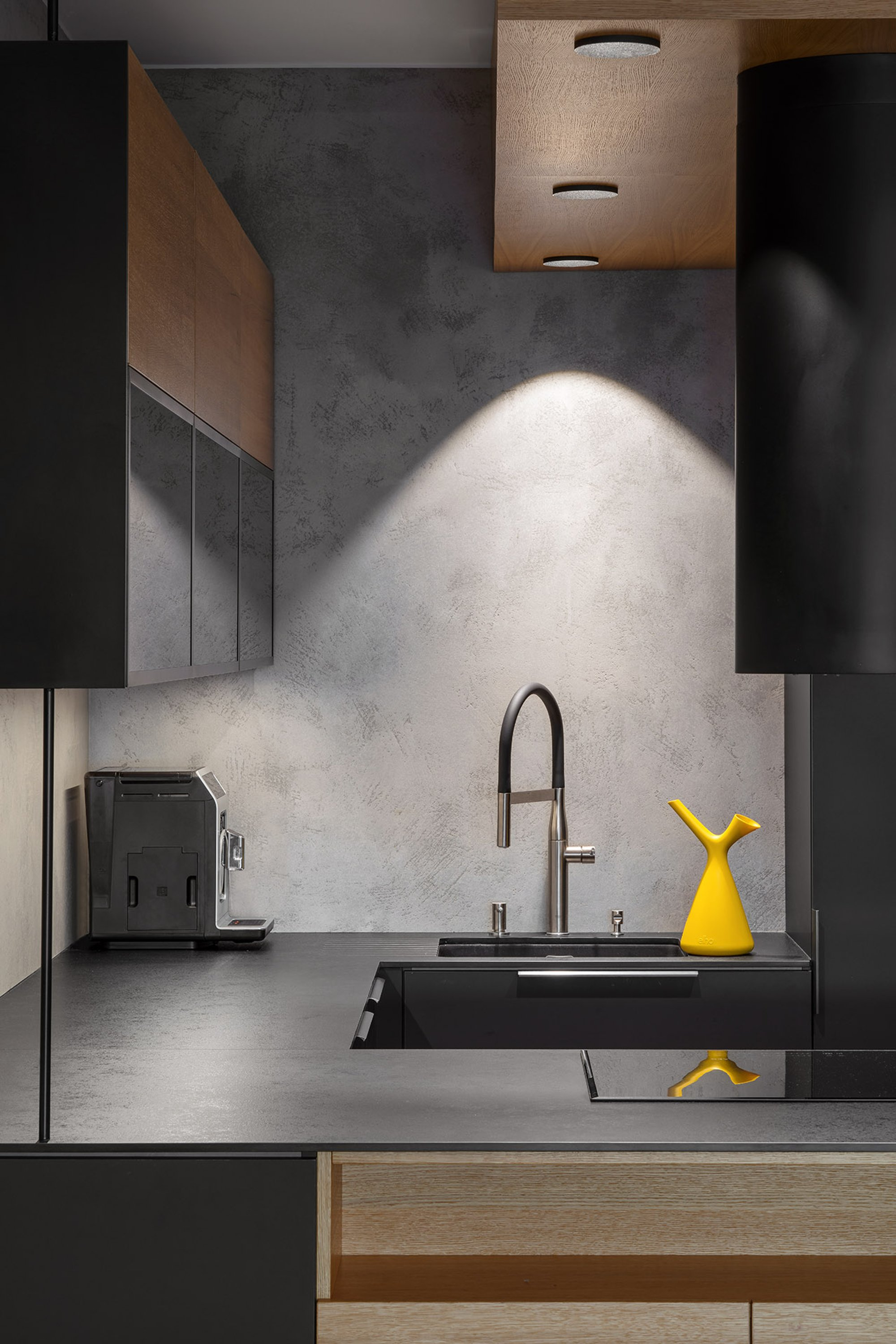 Minimal black kitchen with oak detailing and a bold mustard accent