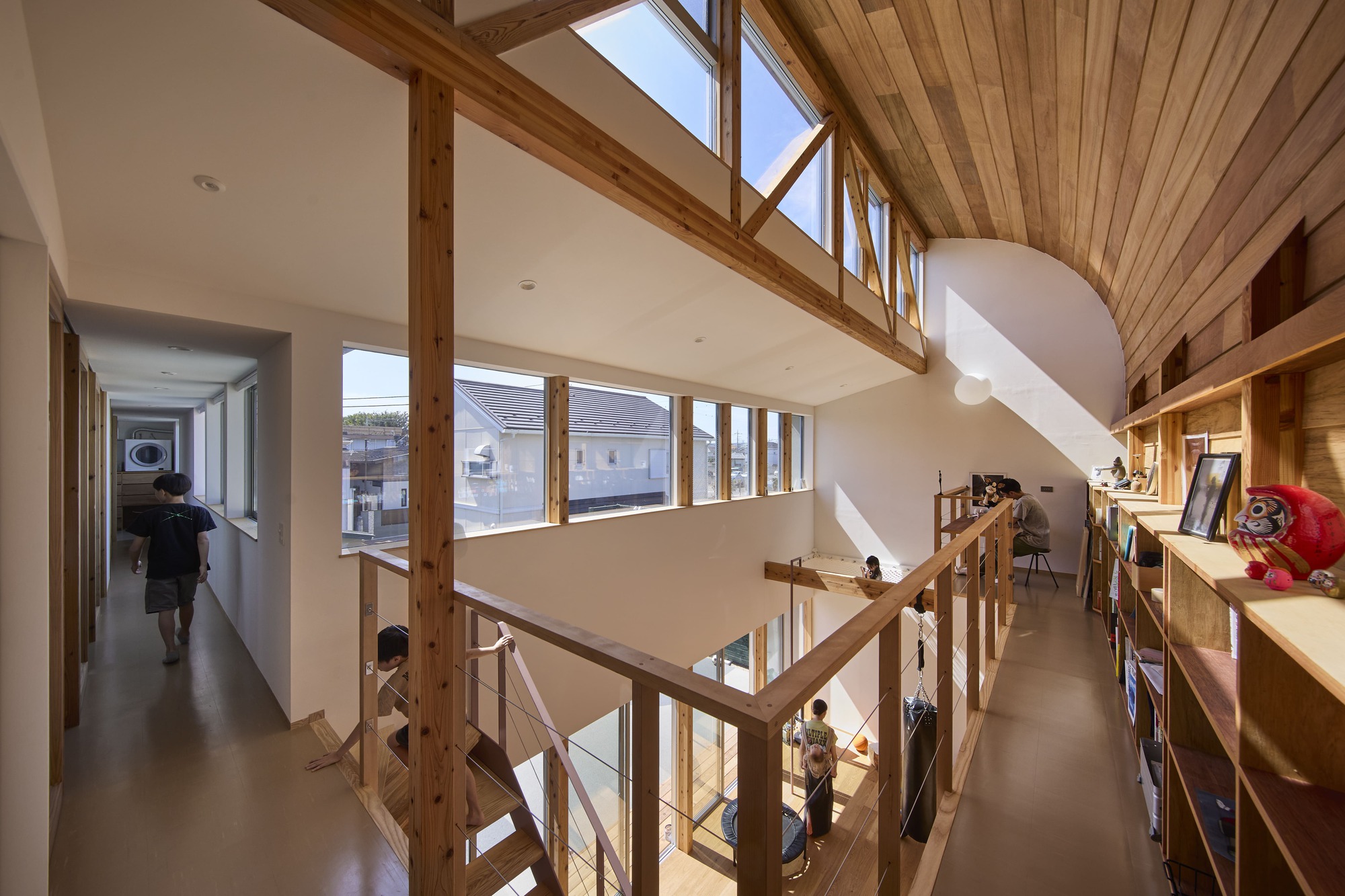 Double-height space with exposed timber frame, clerestory windows and a wooden staircase connecting upper and lower levels