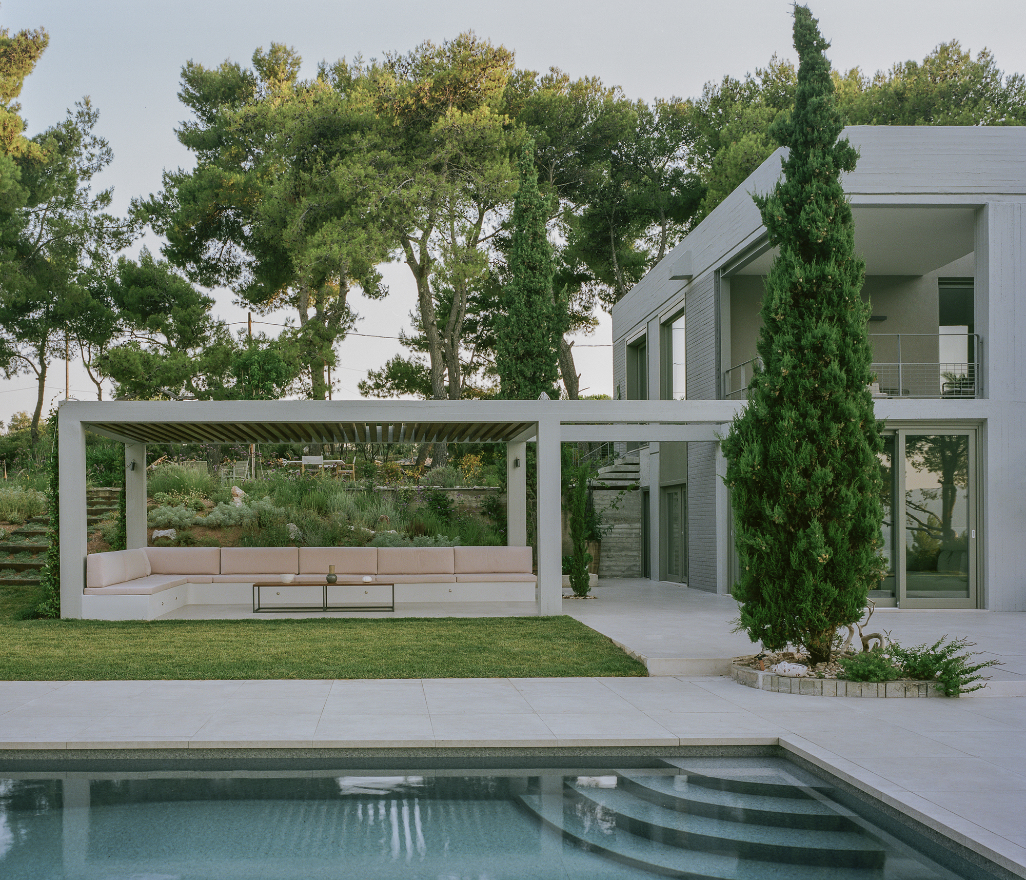 Covered terrace with pink cushioned seating and slatted timber ceiling beside the swimming pool