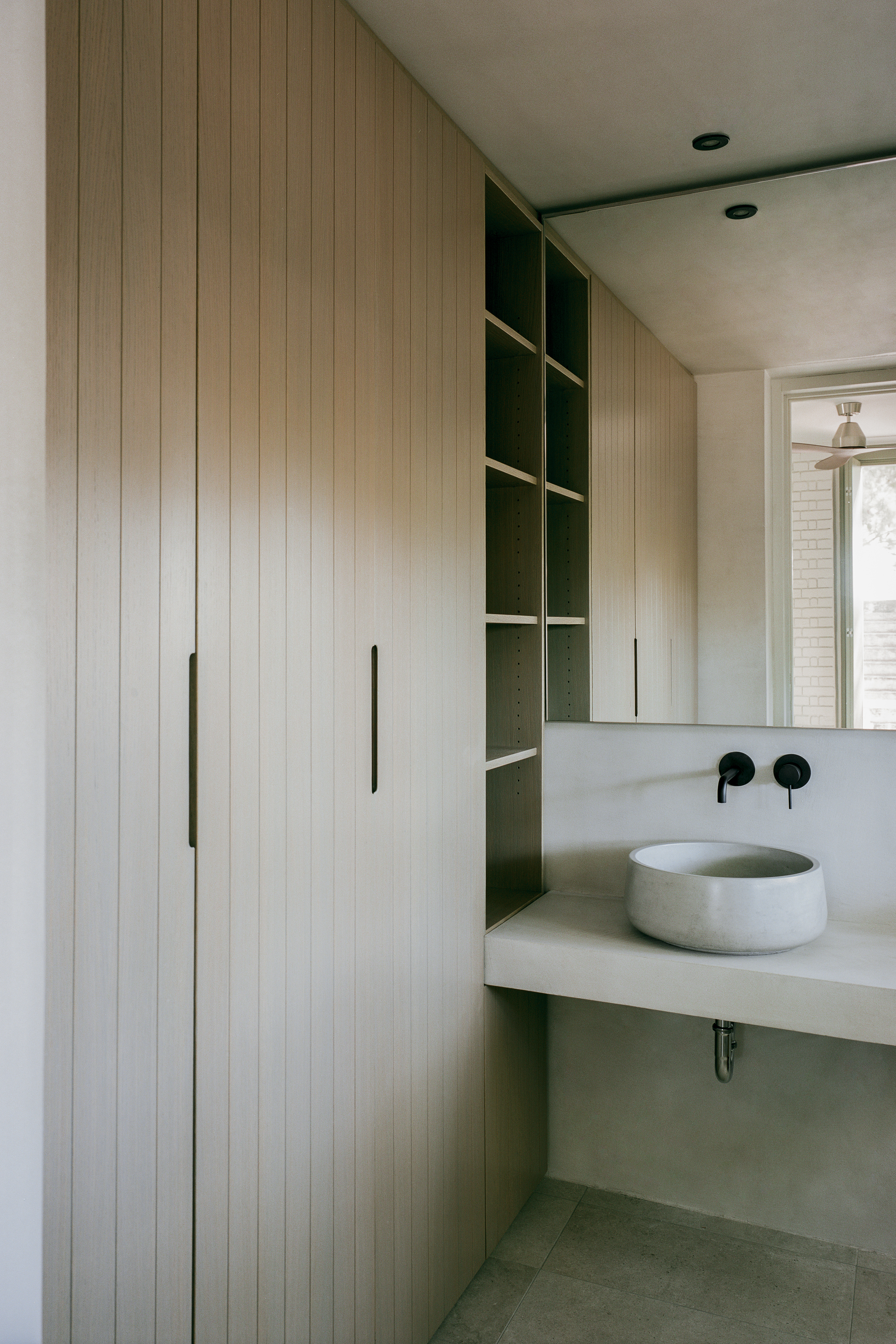 Bathroom vanity with timber cabinetry, open shelving and a round concrete vessel sink