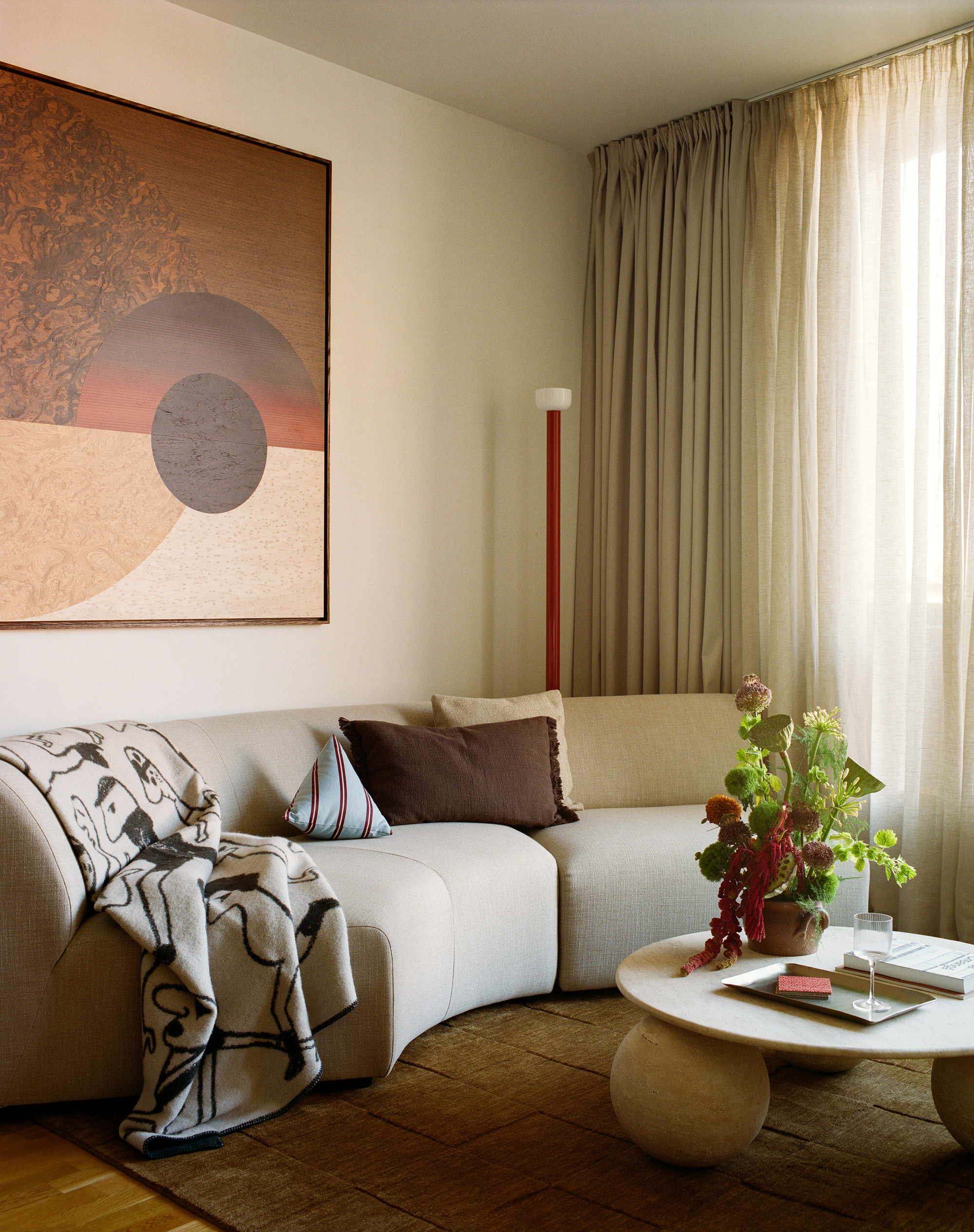 Corner seating area with layered drapery and framed artwork above a curved sofa