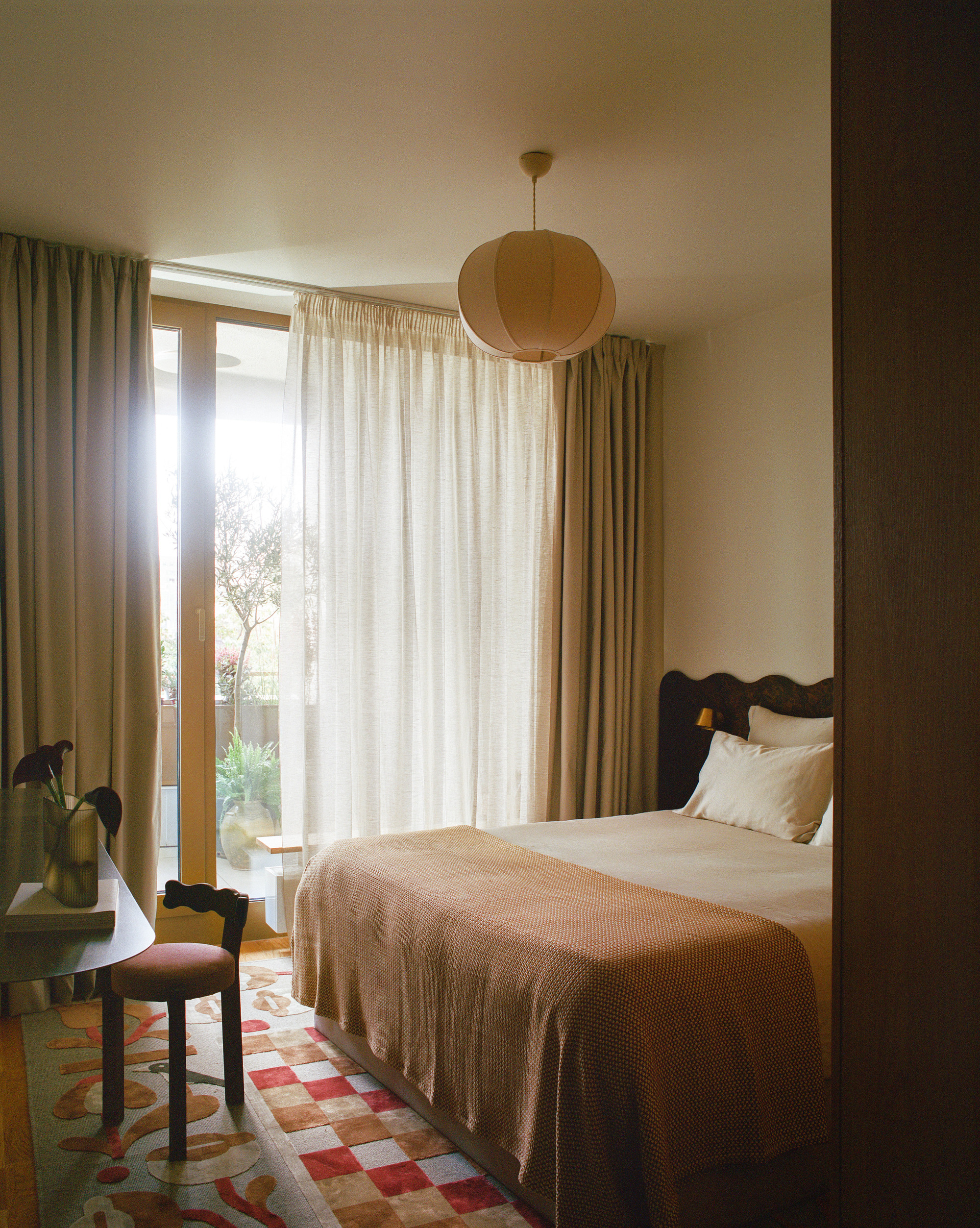 Bedroom with floor-to-ceiling curtains and patterned tile flooring in afternoon light