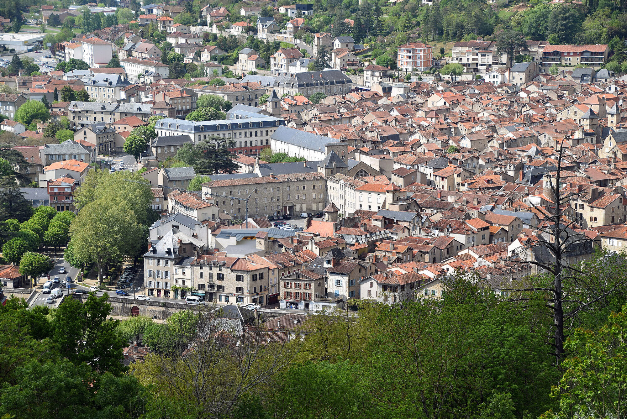 Aerial view of terracotta rooftops clustered in a valley surrounded by green hillsides