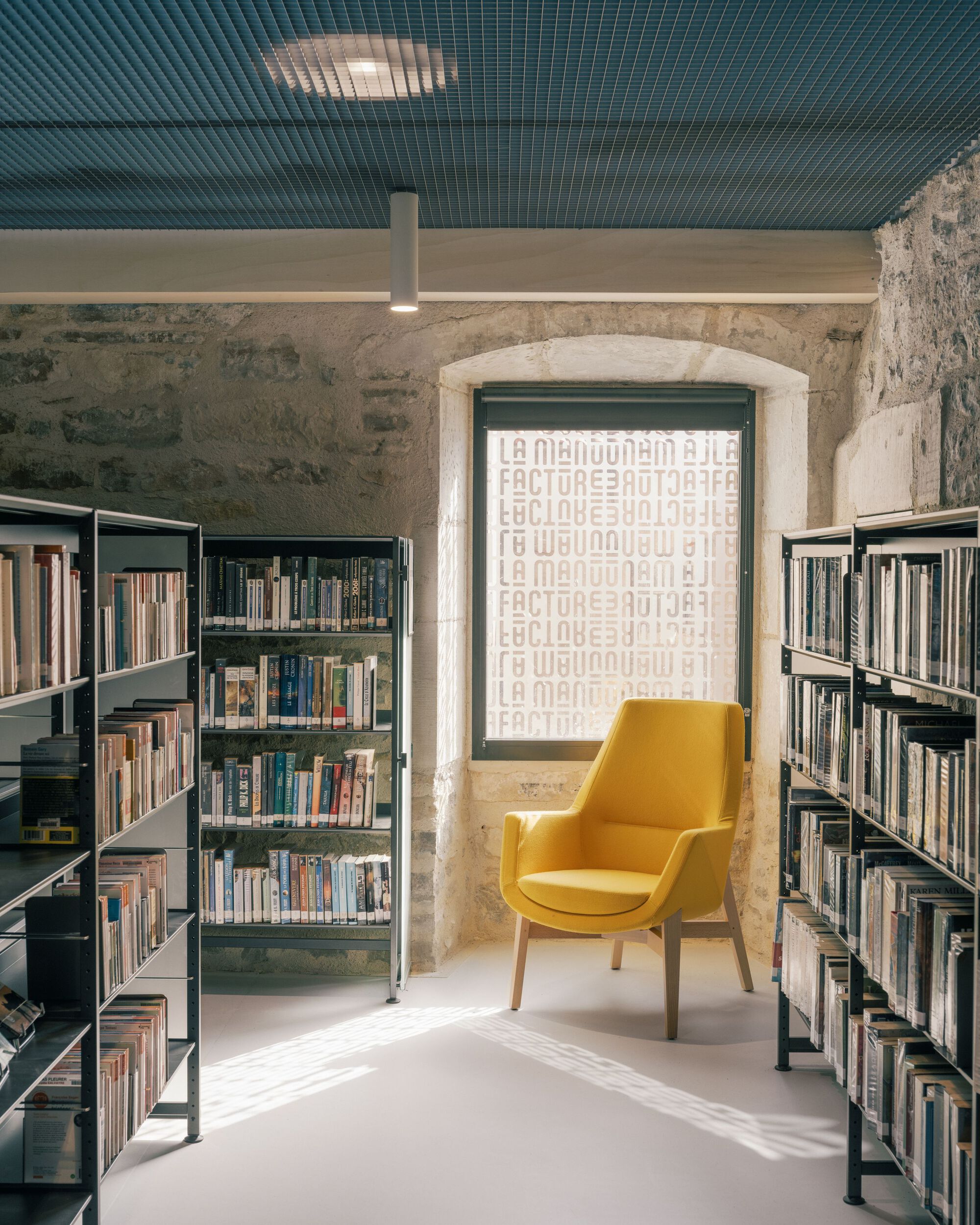 Library alcove with yellow armchair centered beneath an arched window with ribbed ceiling above
