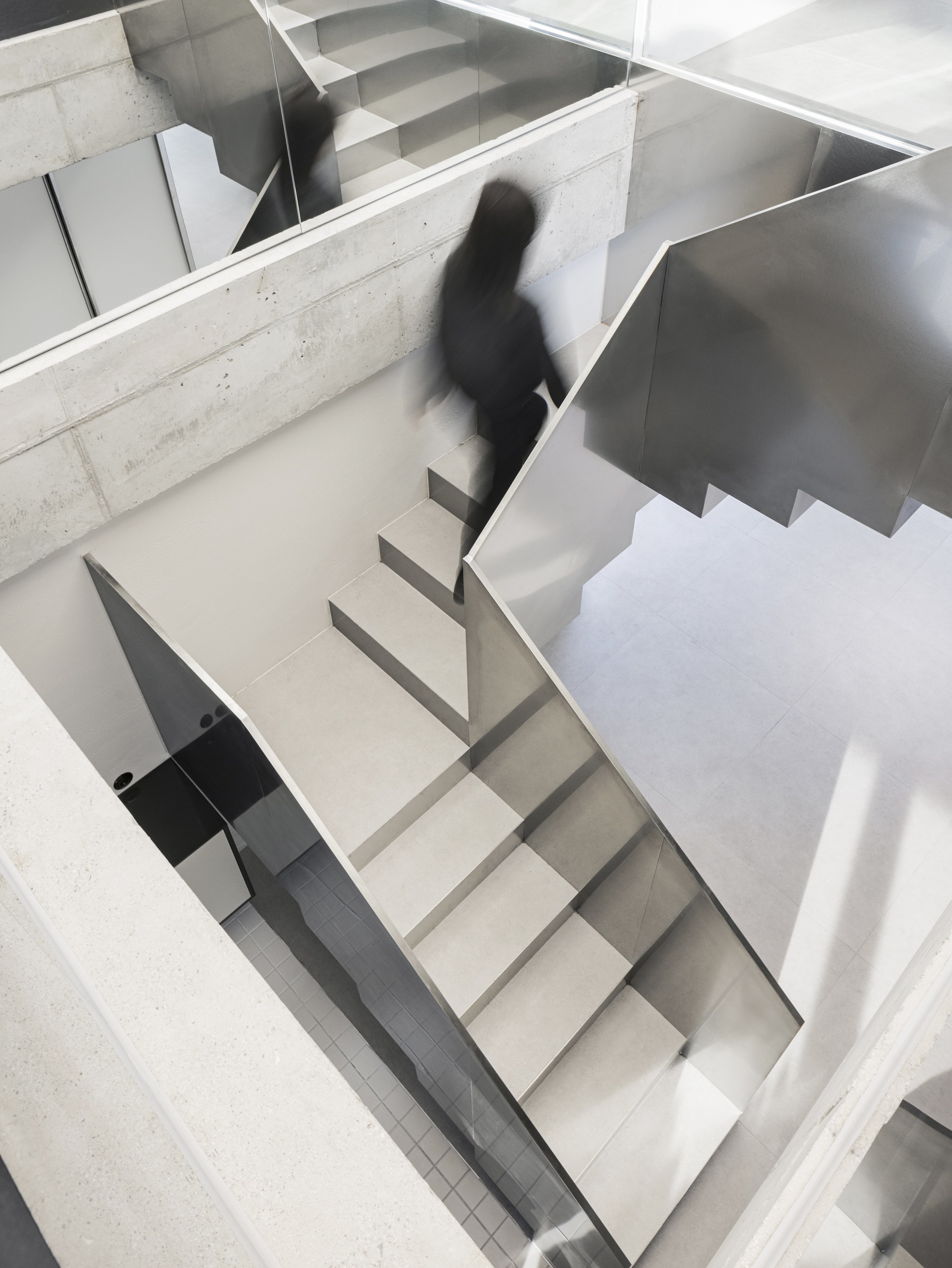 Top-down view of the zigzagging staircase with a figure ascending through the multi-level volume