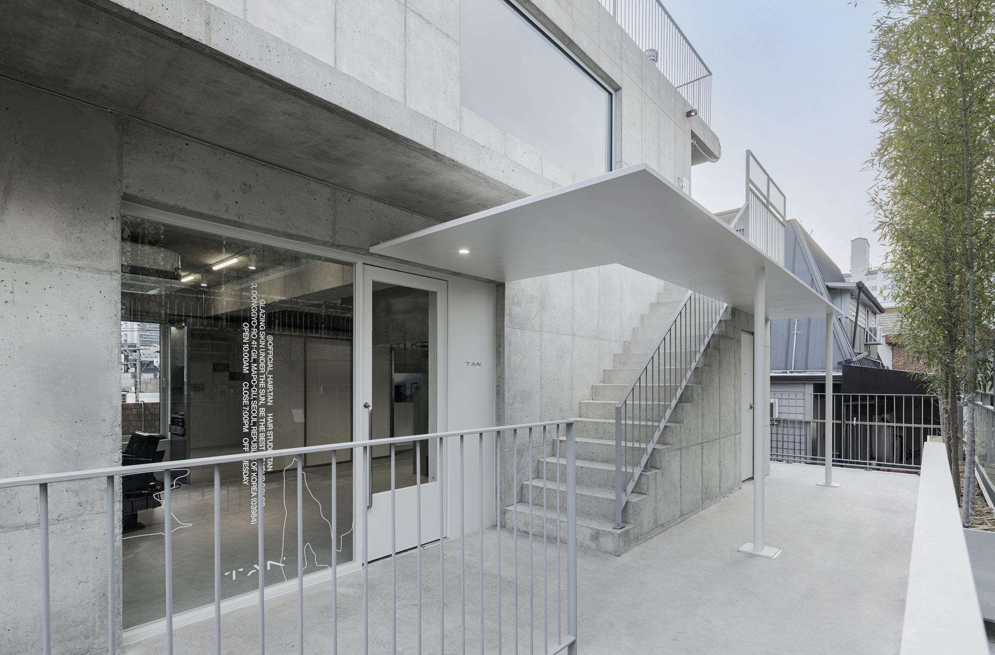 Exterior entrance terrace with metal railings and external stair leading to upper levels in daylight