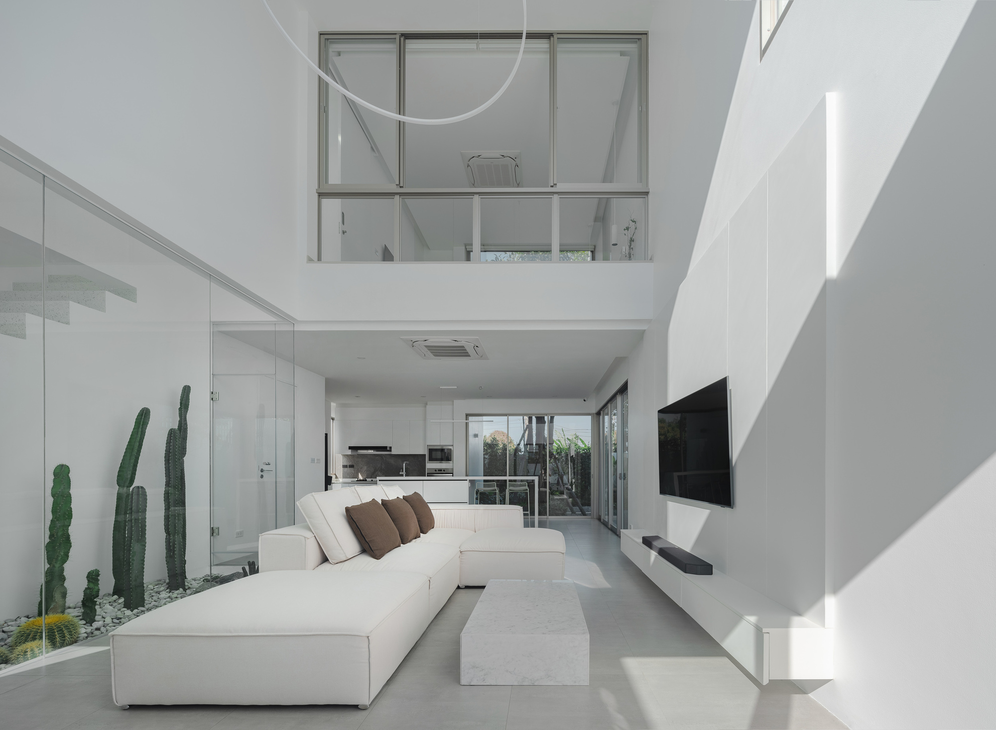 Open-plan living area looking toward kitchen with mezzanine window overlooking the interior volume