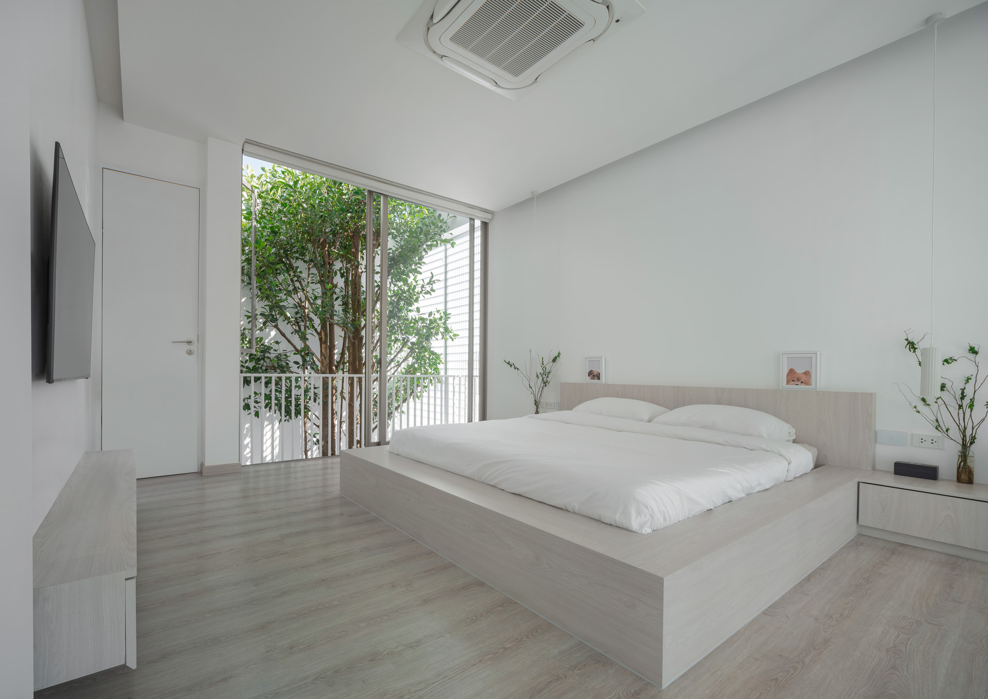 Bedroom with raised platform bed and full-height glazed doors opening to a small tree courtyard