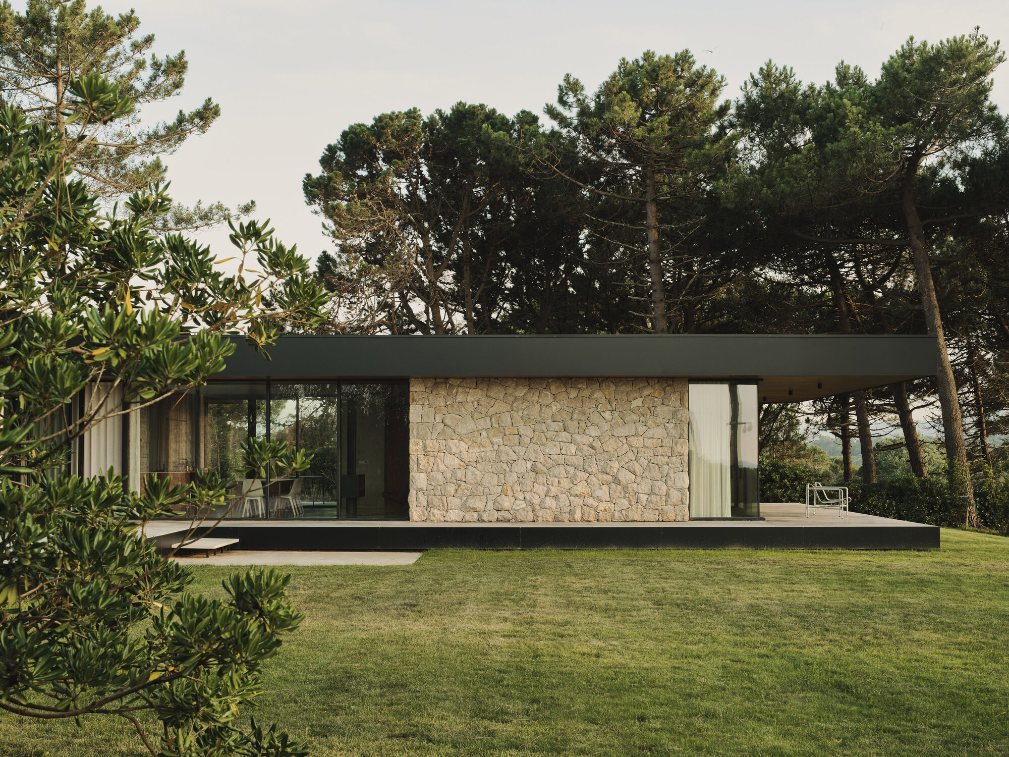 Garden elevation showing stone wall panel flanked by glazing beneath the flat roof overhang