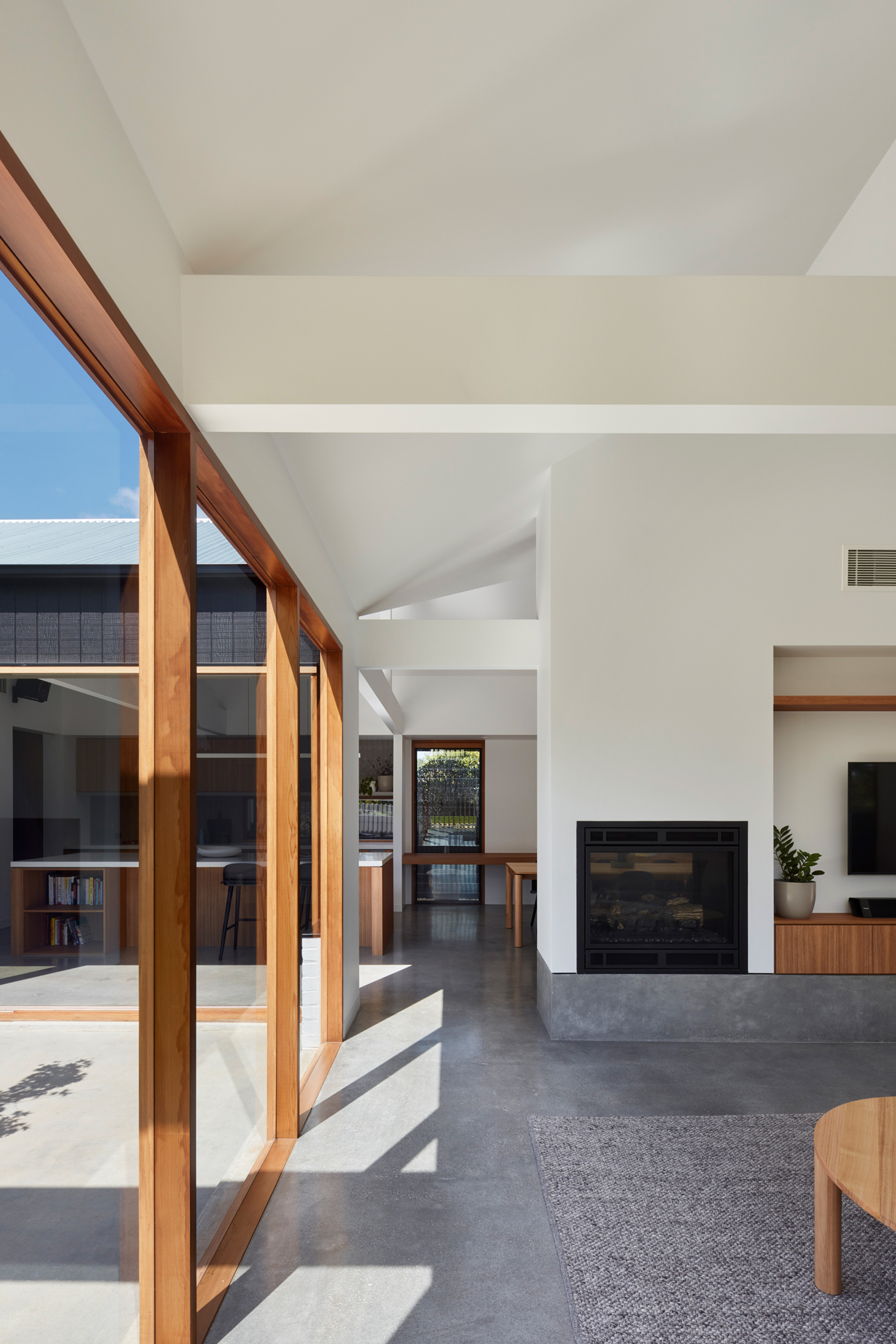 Living area with polished concrete floor and timber framed sliding glass doors opening to the courtyard